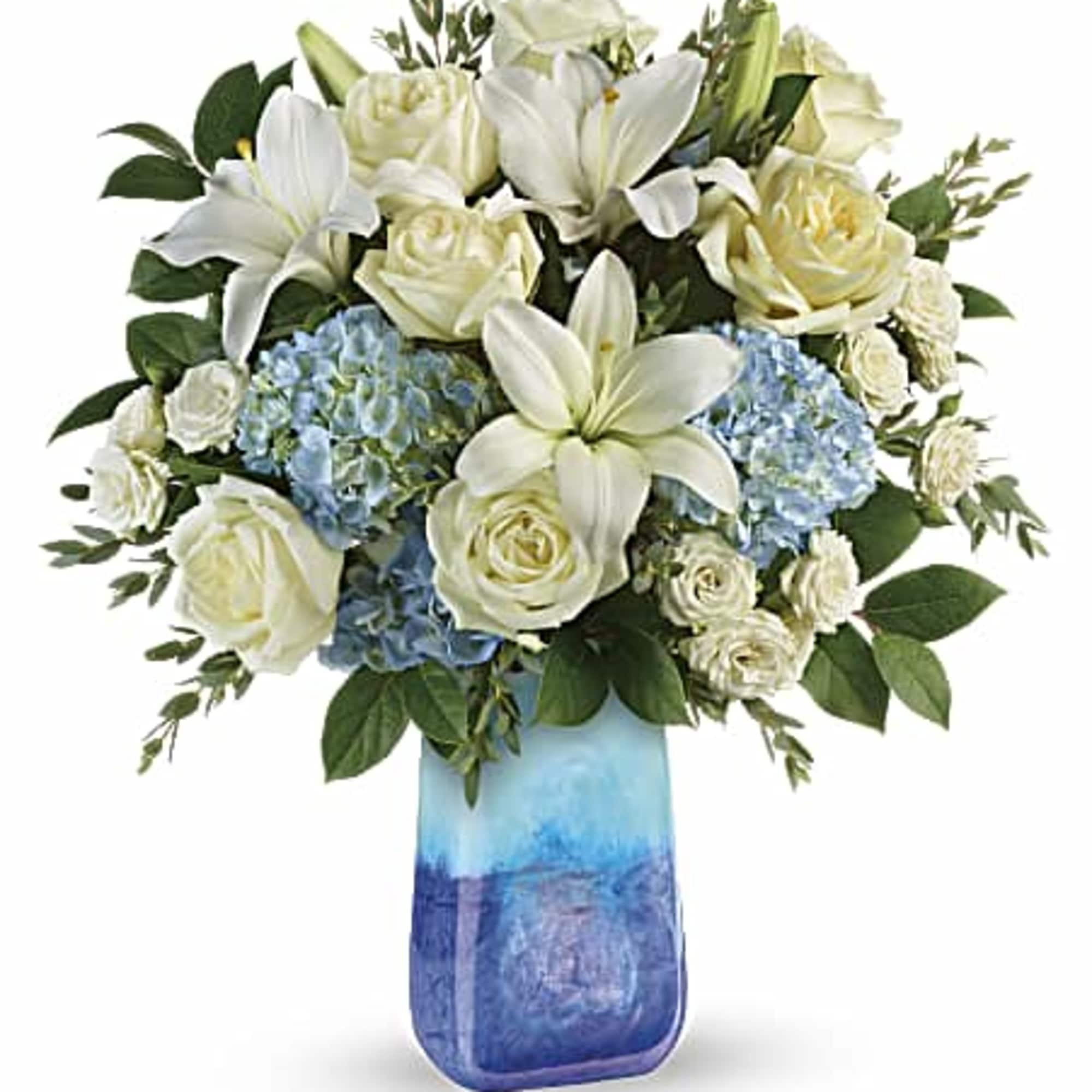 White lilies and roses with blue hydrangeas in a blue glass vase