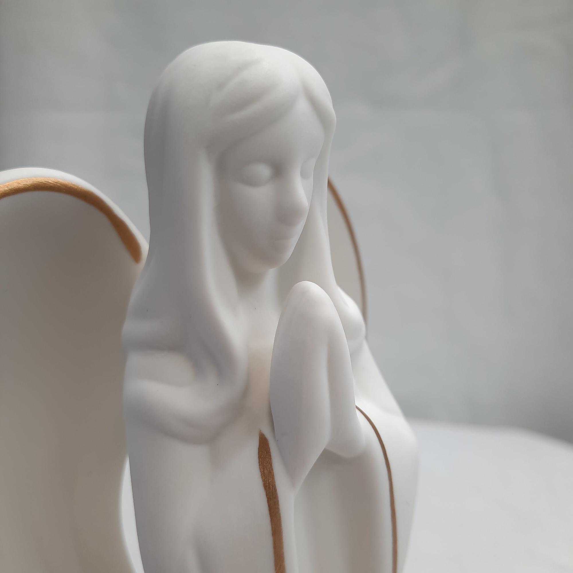 White angel figurine with folded hands and gold trim
