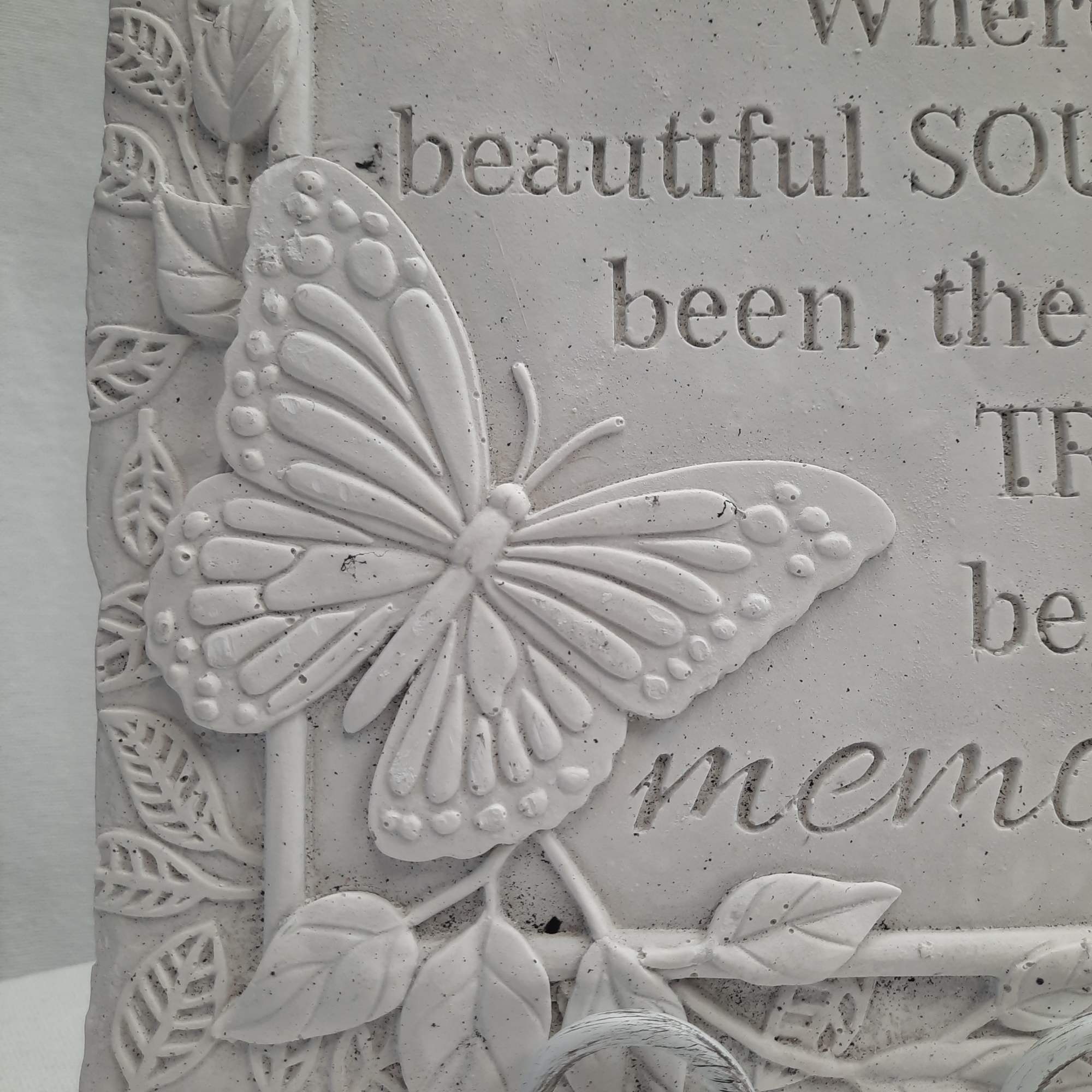 White butterfly relief on a textured plaque with raised lettering