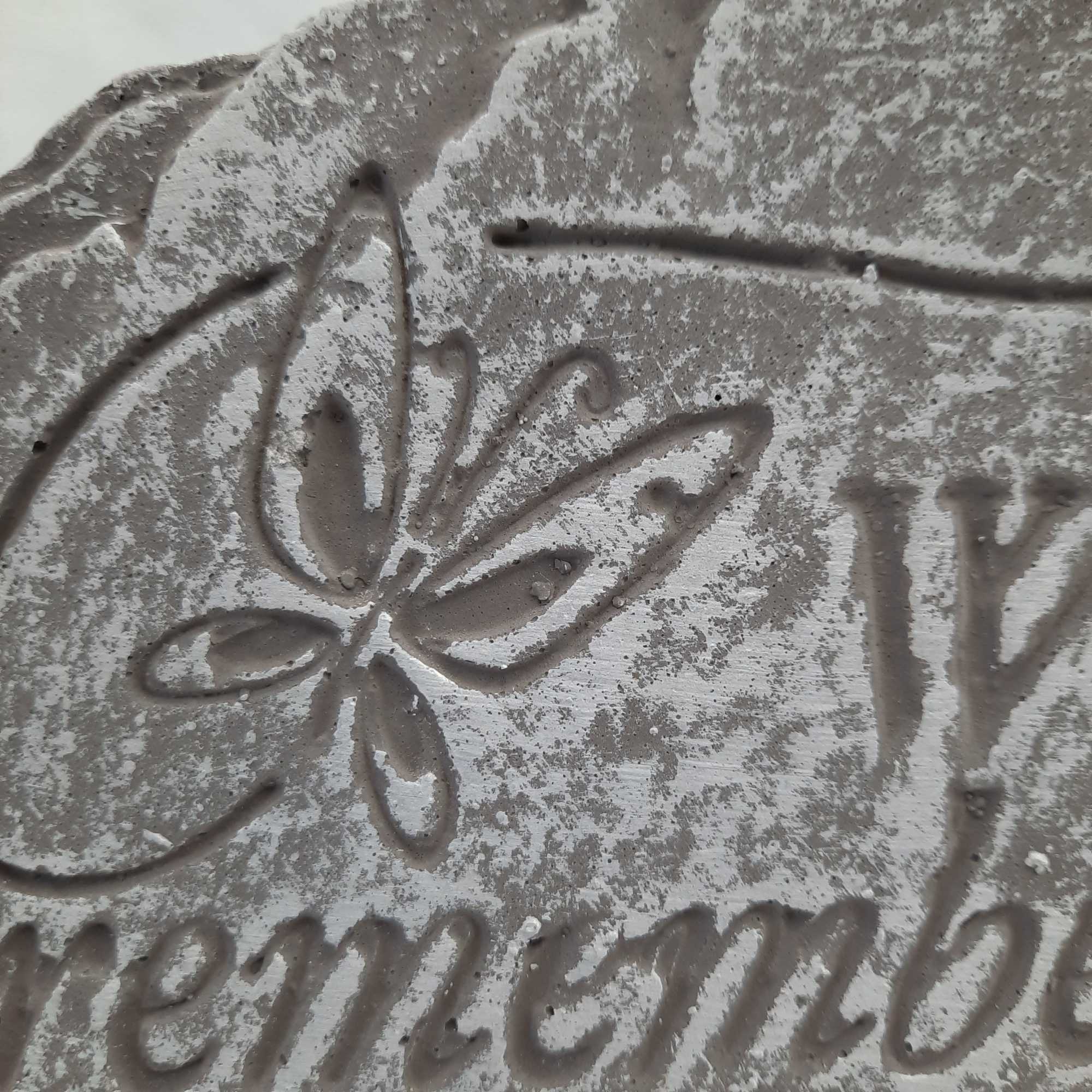 Close-up of a gray textured surface with an embossed floral design and partial lettering.