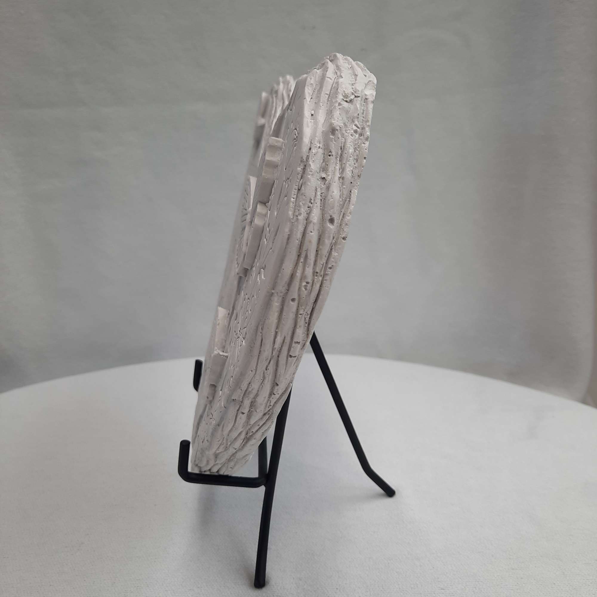 White textured decorative object on a black display stand
