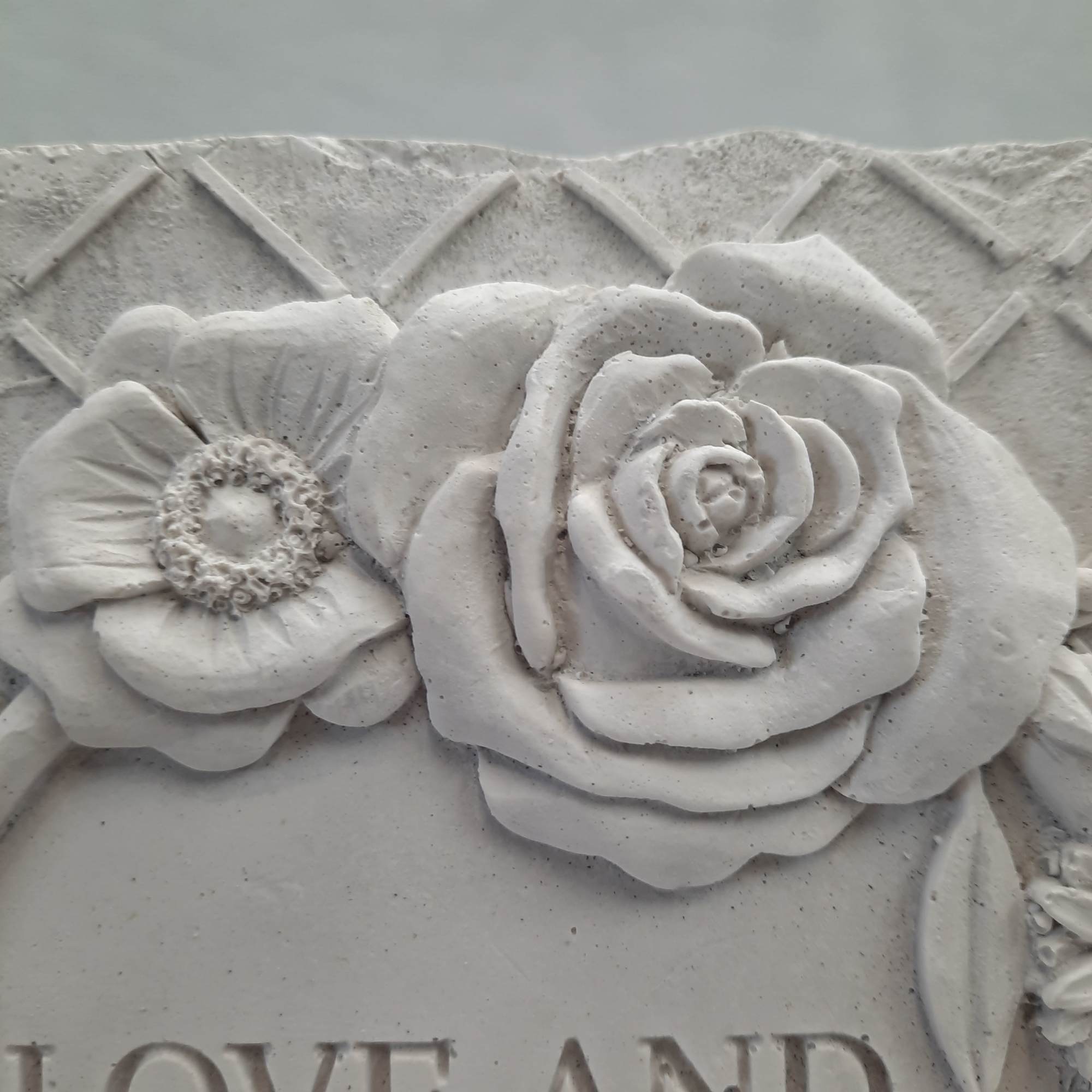 White floral relief sculpture with a rose and poppy-like bloom