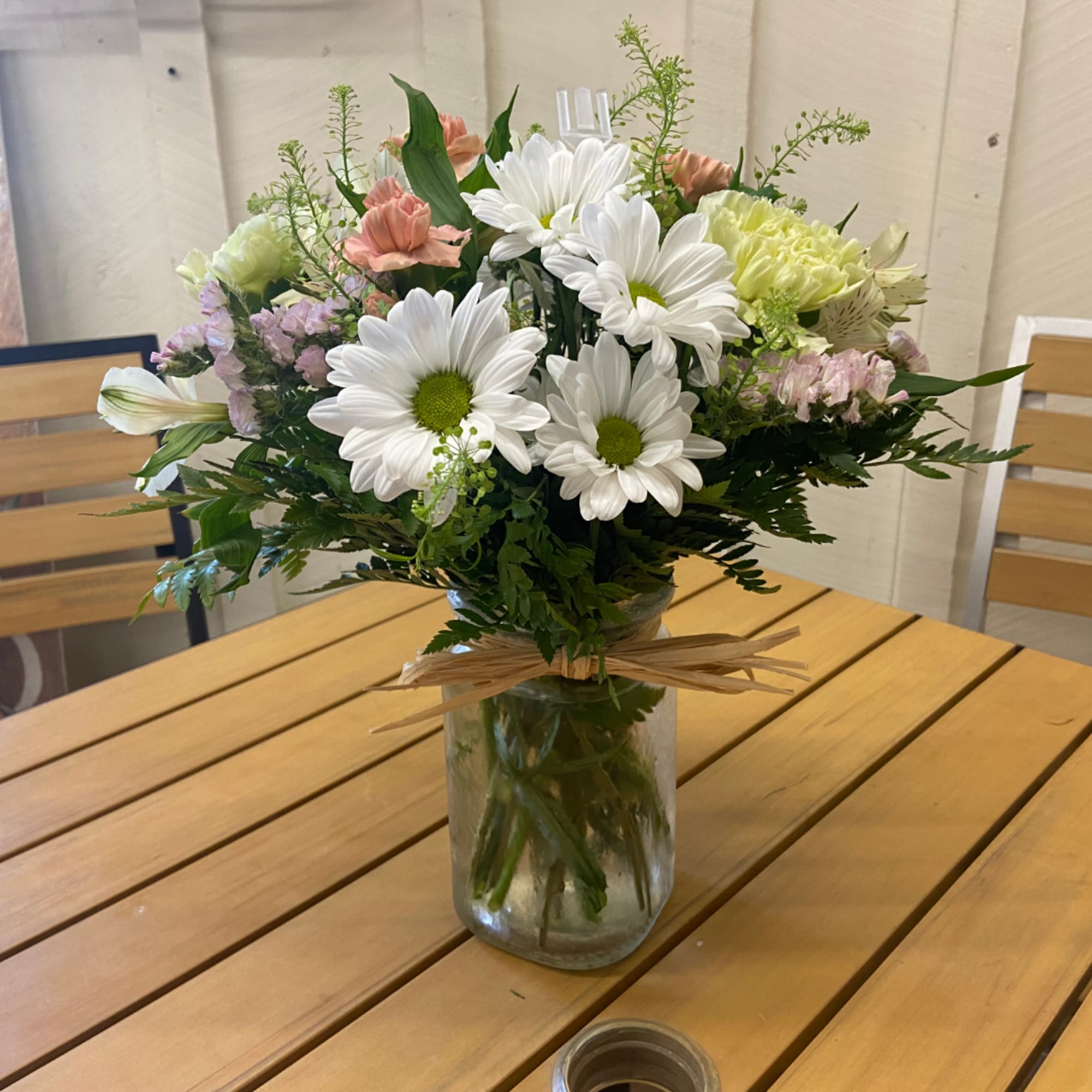 Mixed bouquet of white daisies and pastel flowers in a glass vase