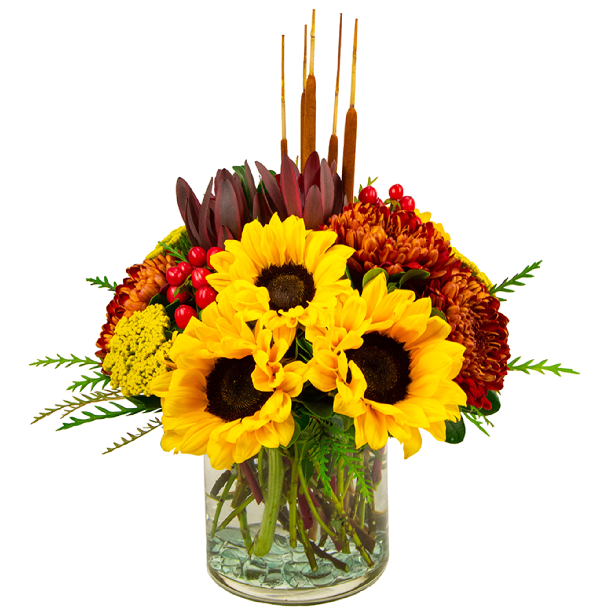 Sunflowers and autumn flowers in a clear glass vase with cattails
