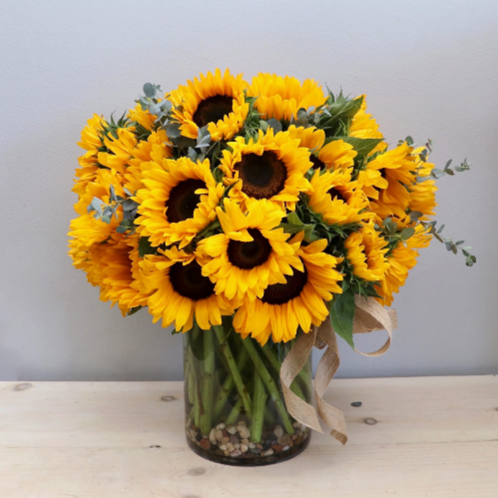 Bouquet of yellow sunflowers in a glass vase with a ribbon