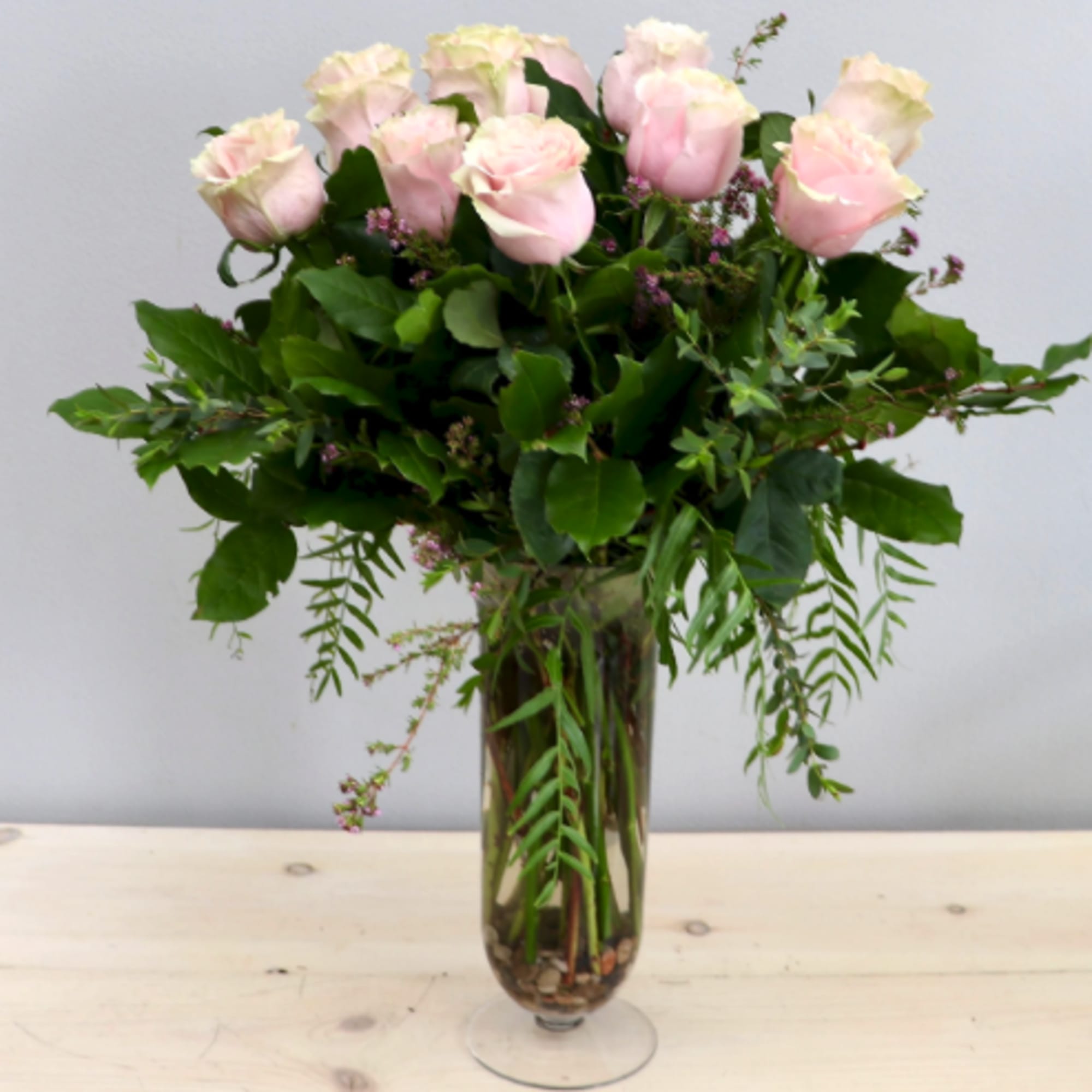 Tall arrangement of pale pink roses in a clear glass vase