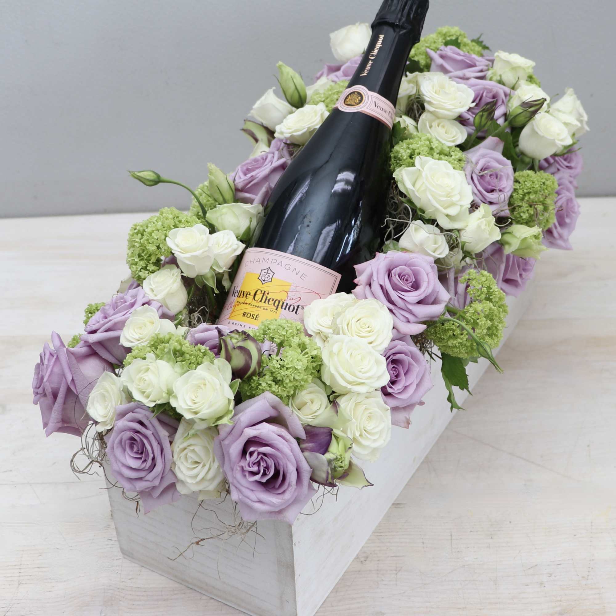Lavender and white roses arranged around a champagne bottle in a white box, photo 2 of 4