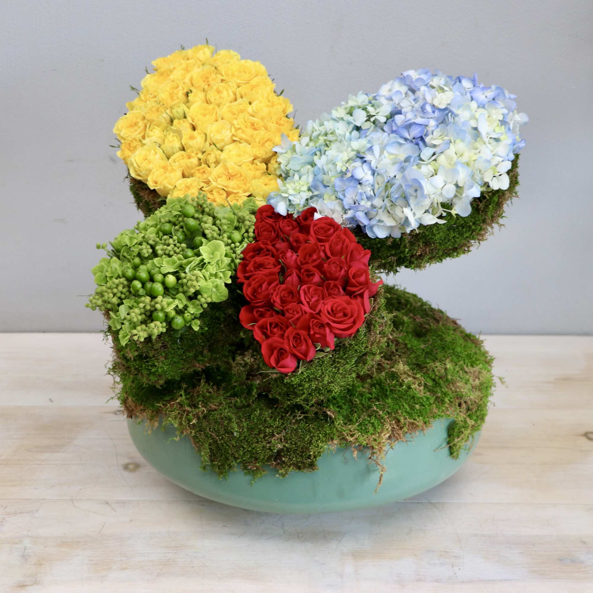 Colorful floral arrangement in a turquoise bowl with moss-covered sections