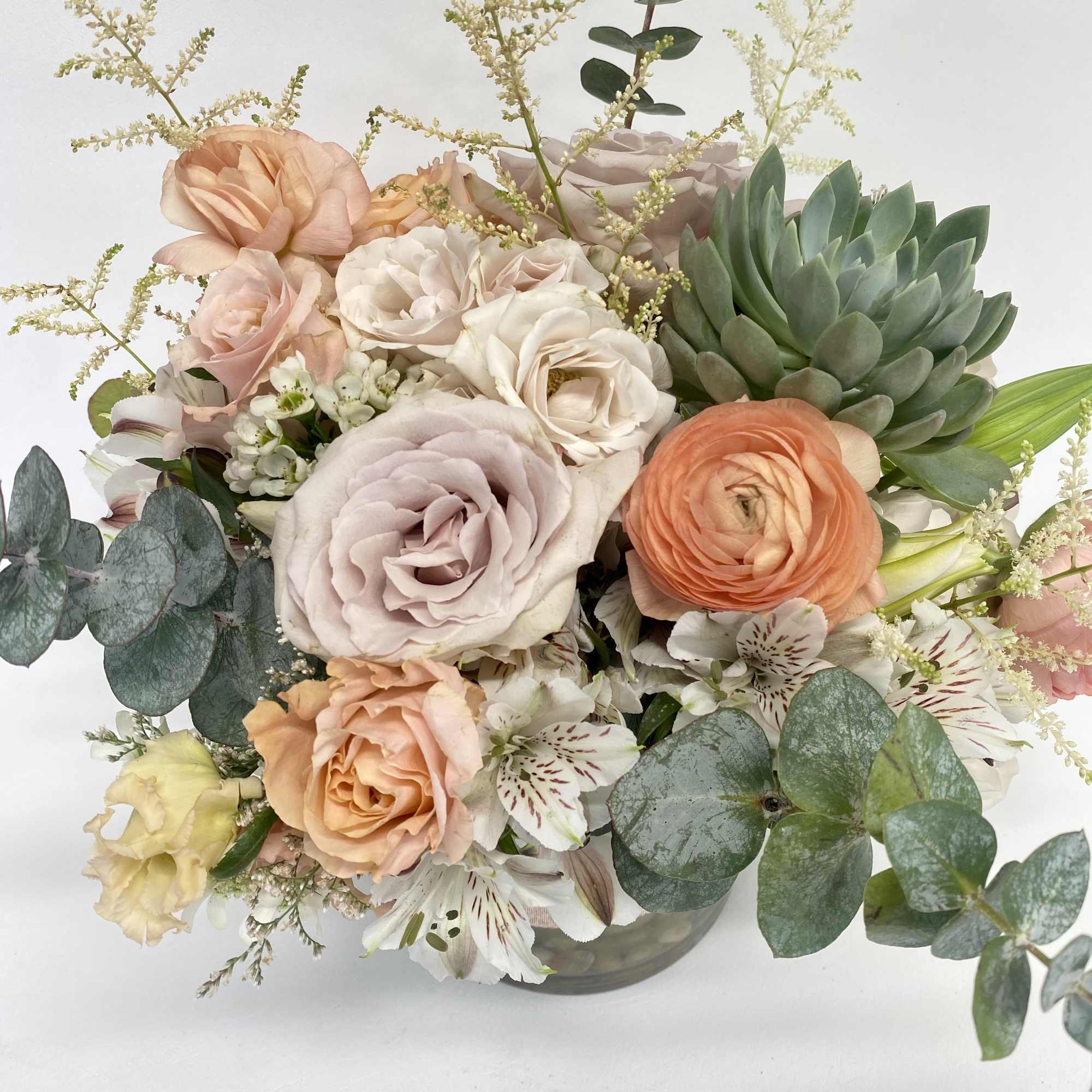 Pastel bouquet of roses, ranunculus, and alstroemeria in a glass vase