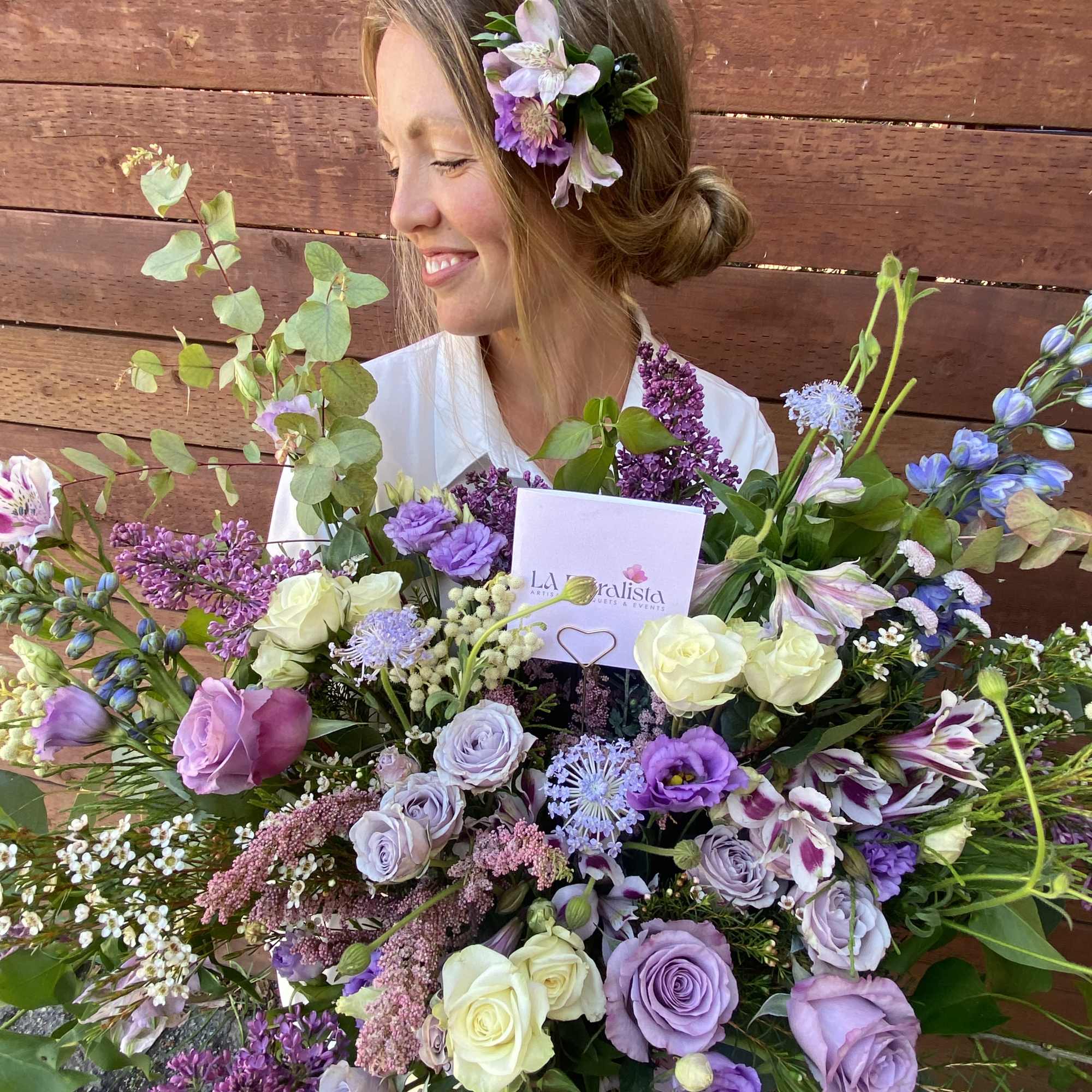 Woman holding a large bouquet of purple and white flowers