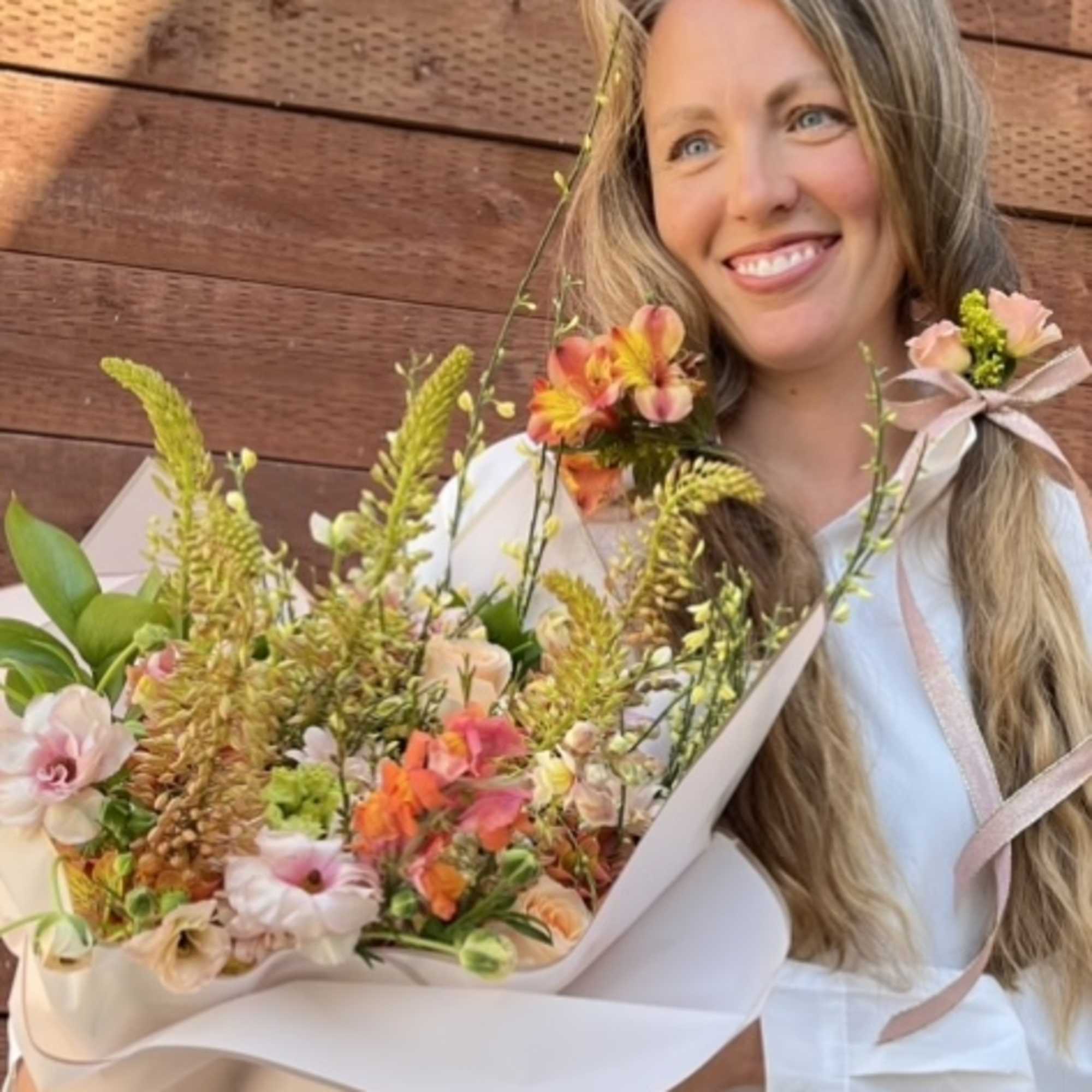 Woman holding a pastel bouquet with ribbon and mixed flowers