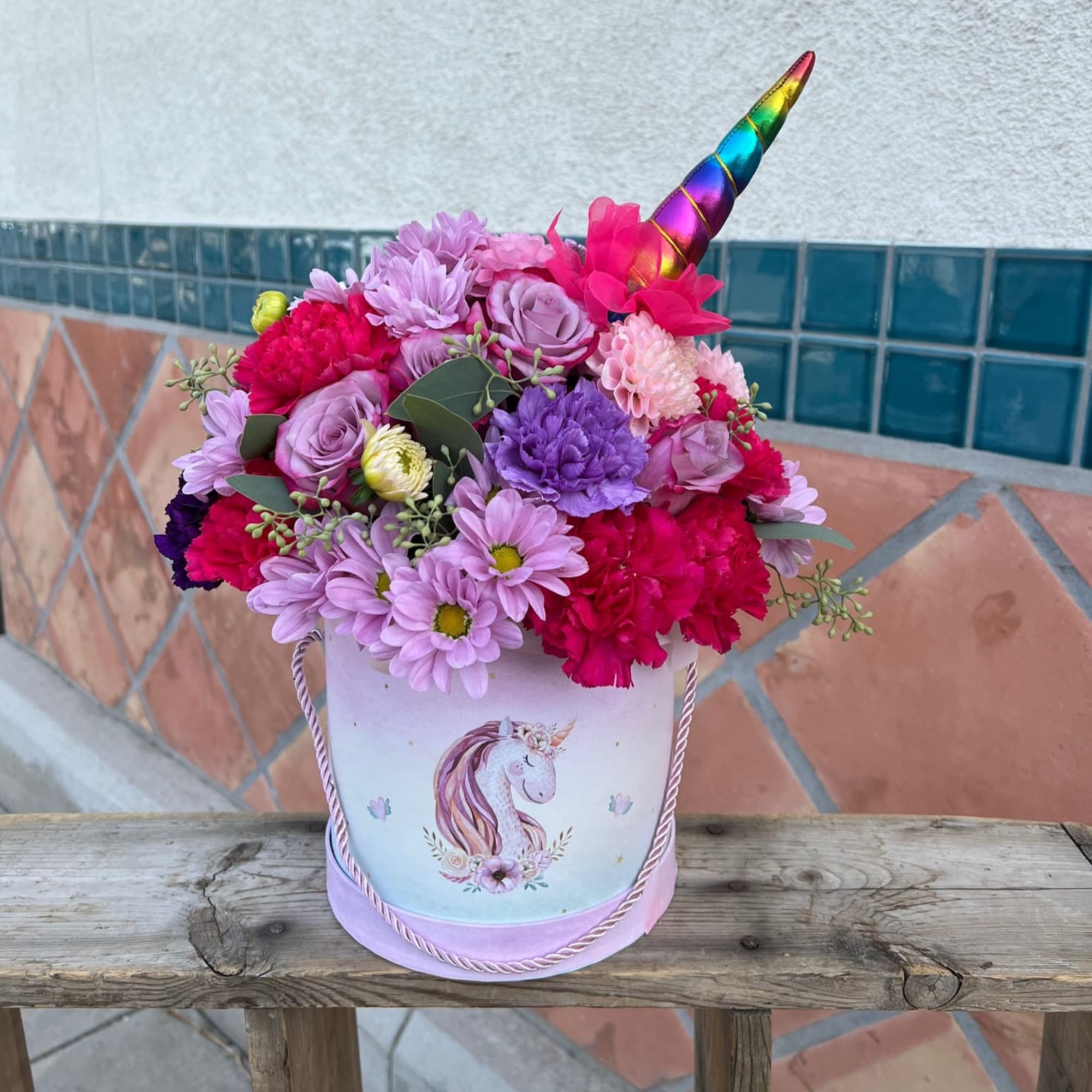 Colorful flower arrangement in a unicorn bucket with a rainbow horn