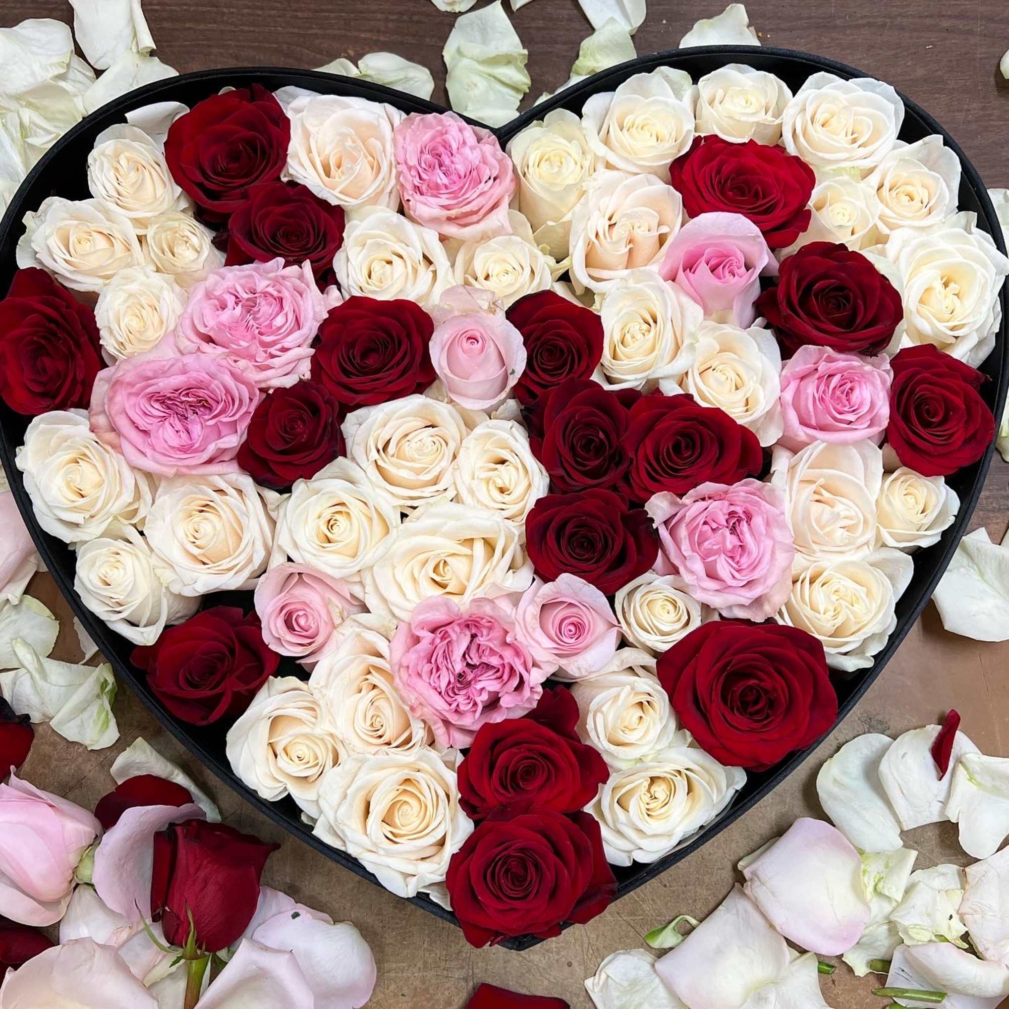 Heart-shaped box filled with red, white, and pink roses