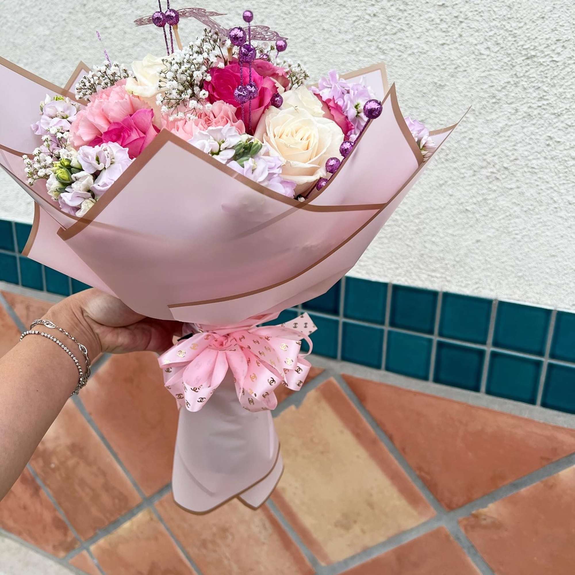 Pink and white bouquet with roses and small filler flowers in pastel wrapping