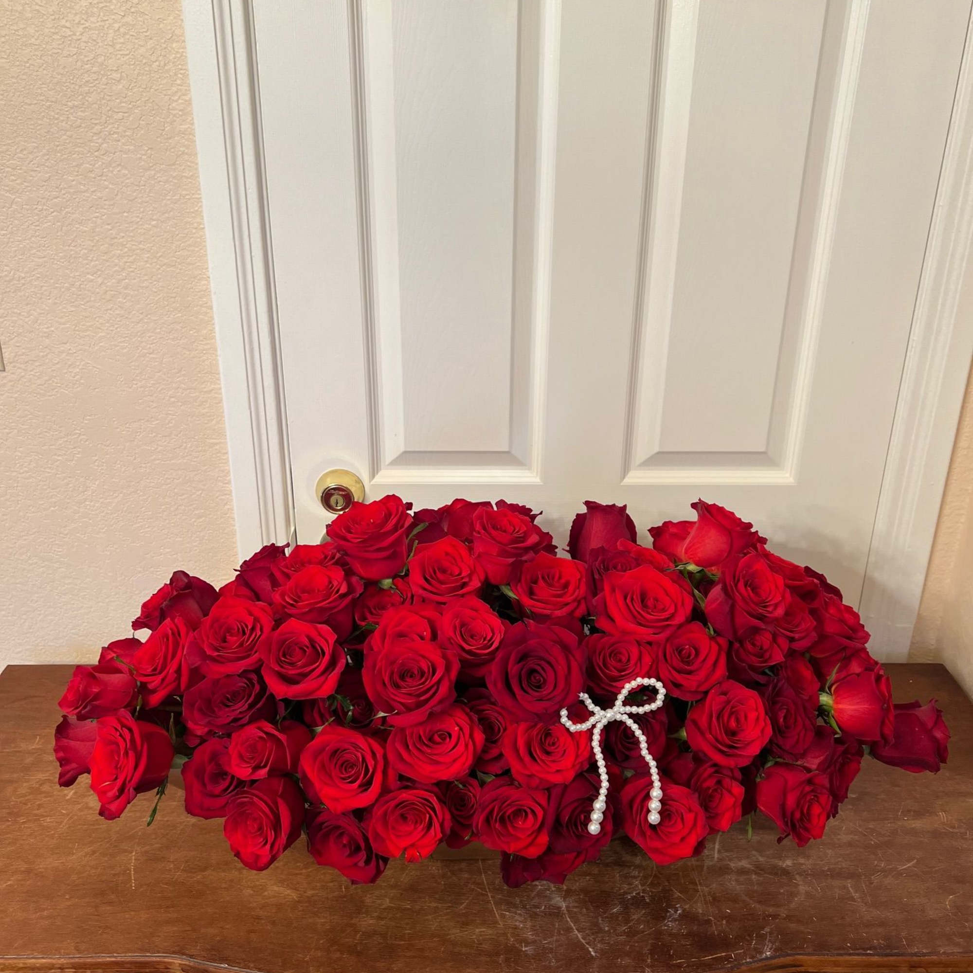 Large arrangement of red roses with a pearl bow accent