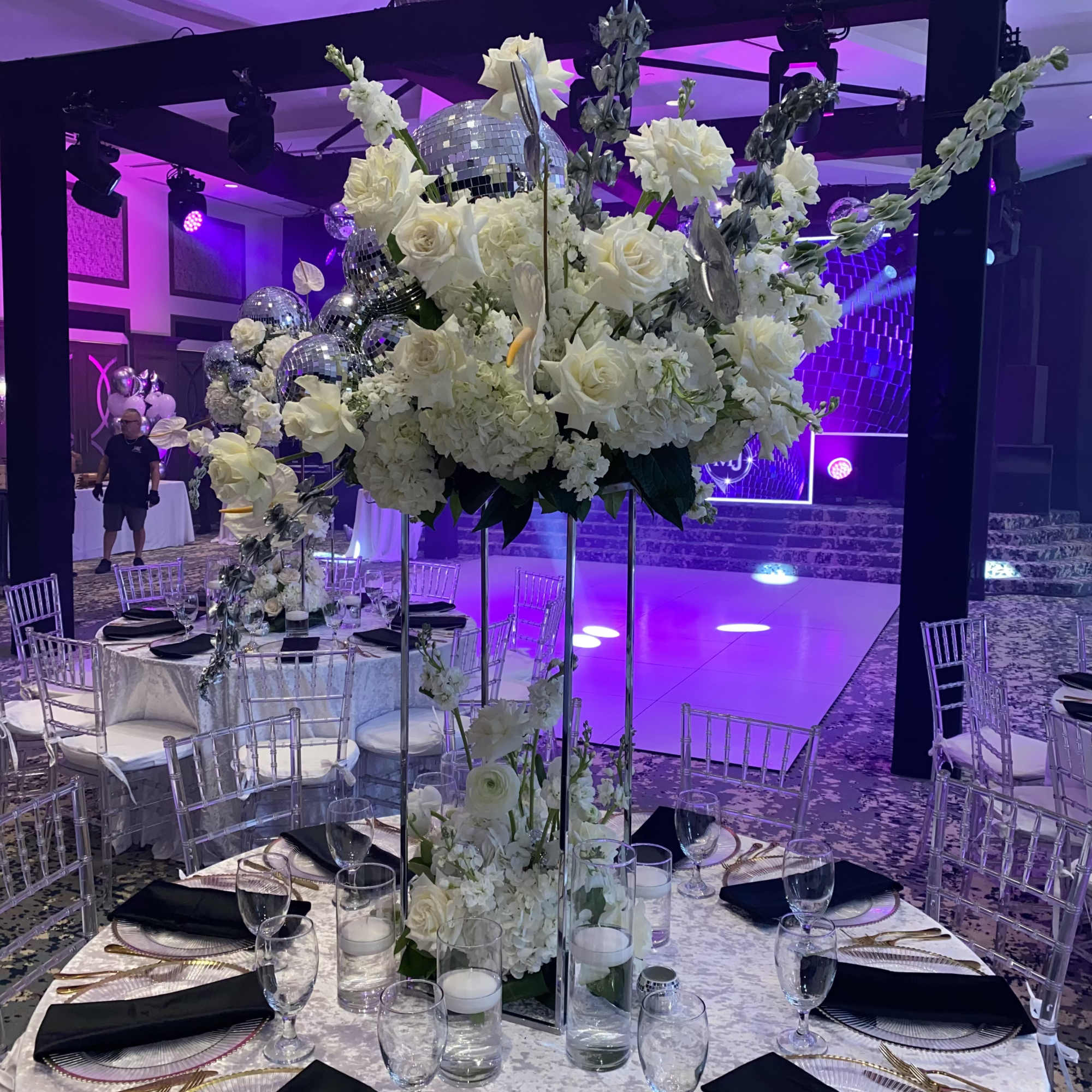 Tall white floral centerpiece on a banquet table with mirrored accents