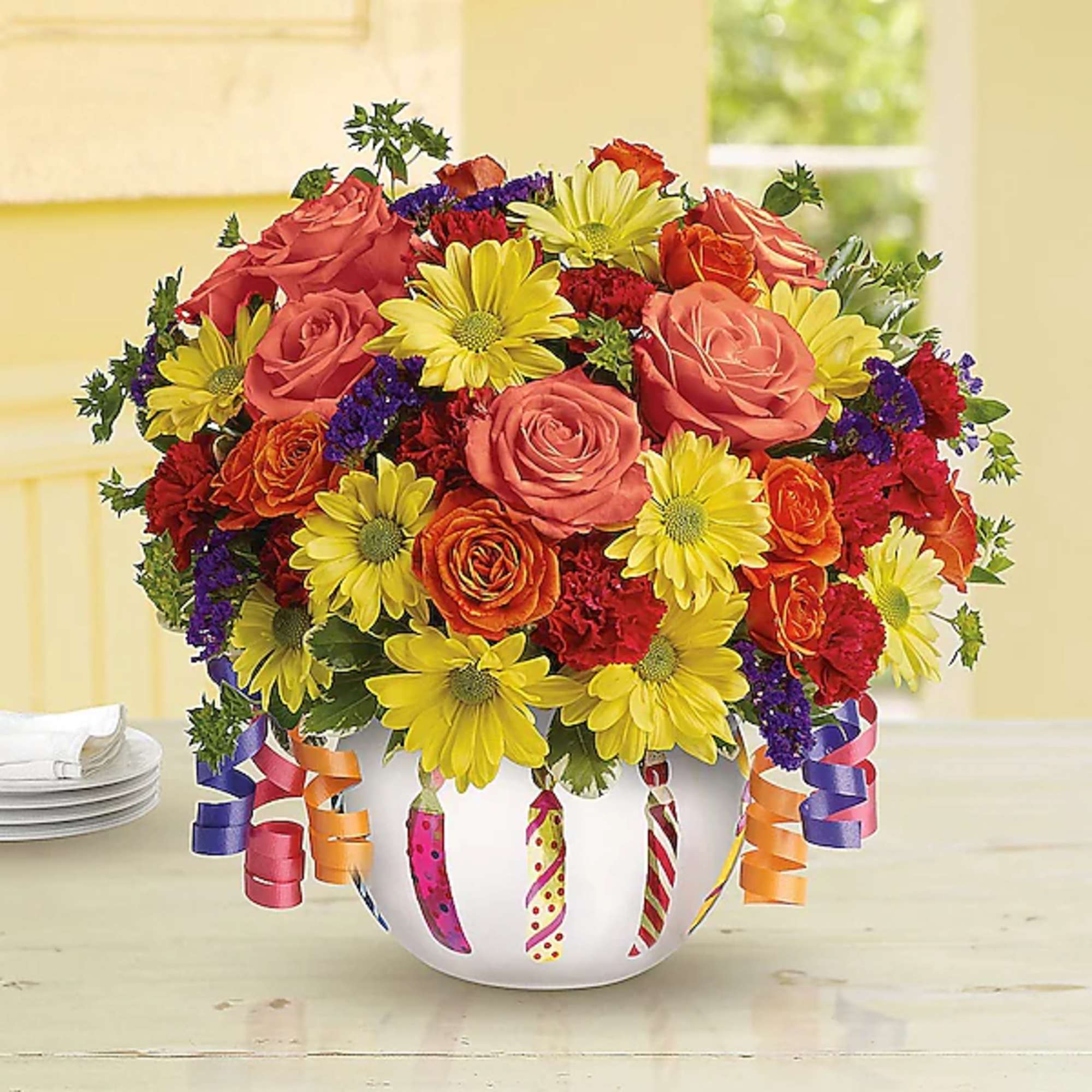 Mixed bouquet of roses, daisies, and carnations in a decorated white vase