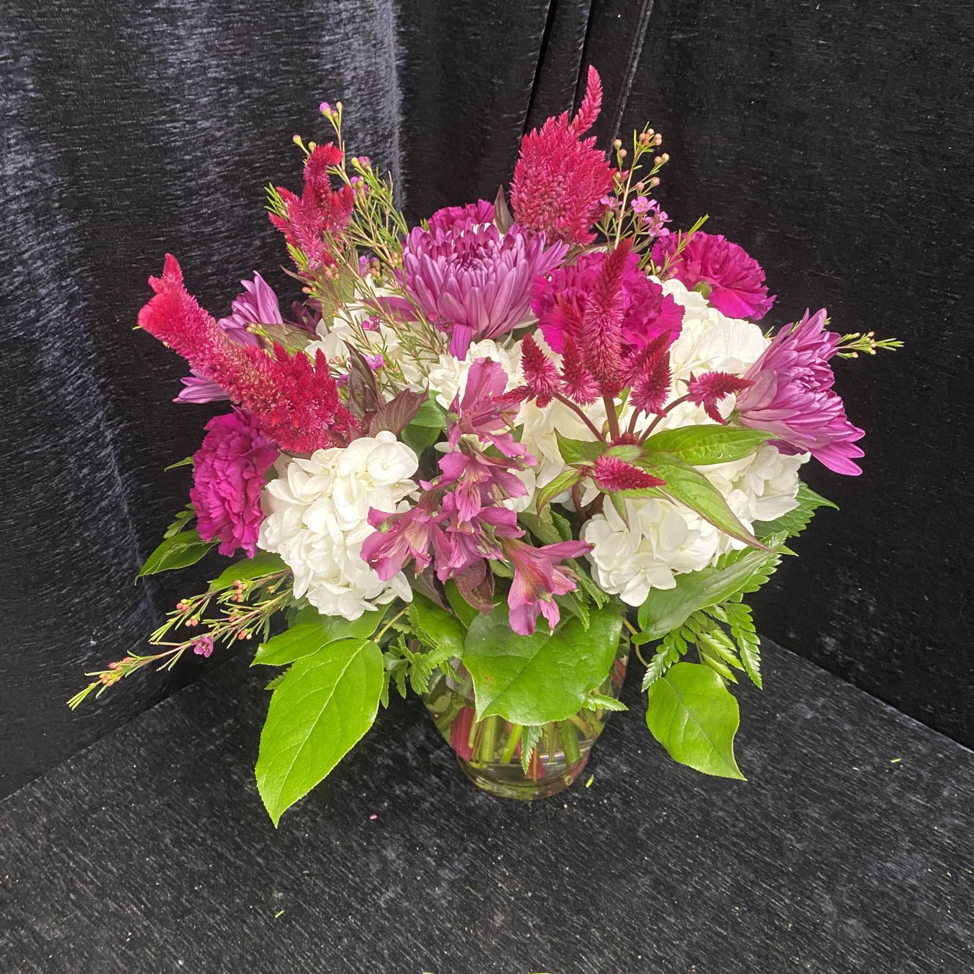 Arrangement includes White Hydrangea, Purple Spiders, Fuscia Carnations, Fuscia Alstromeria and Wax