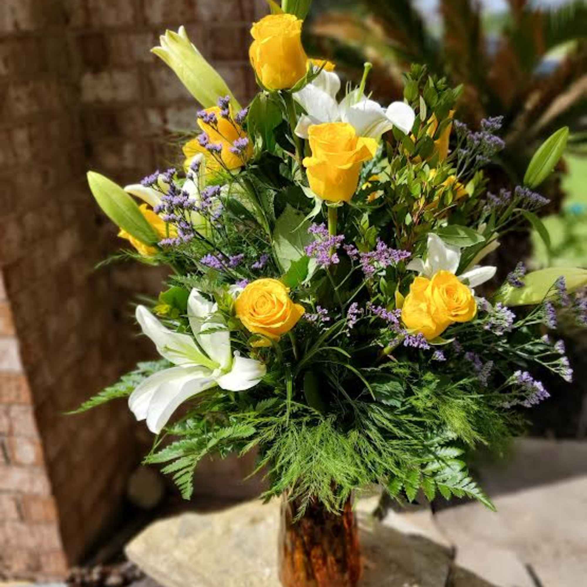 Yellow roses and white lilies in a glass vase