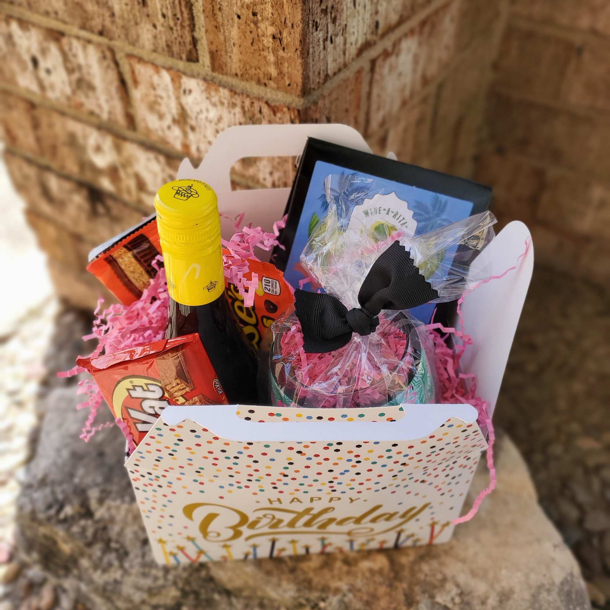 Birthday gift basket with candy, a bottle, and a wrapped treat