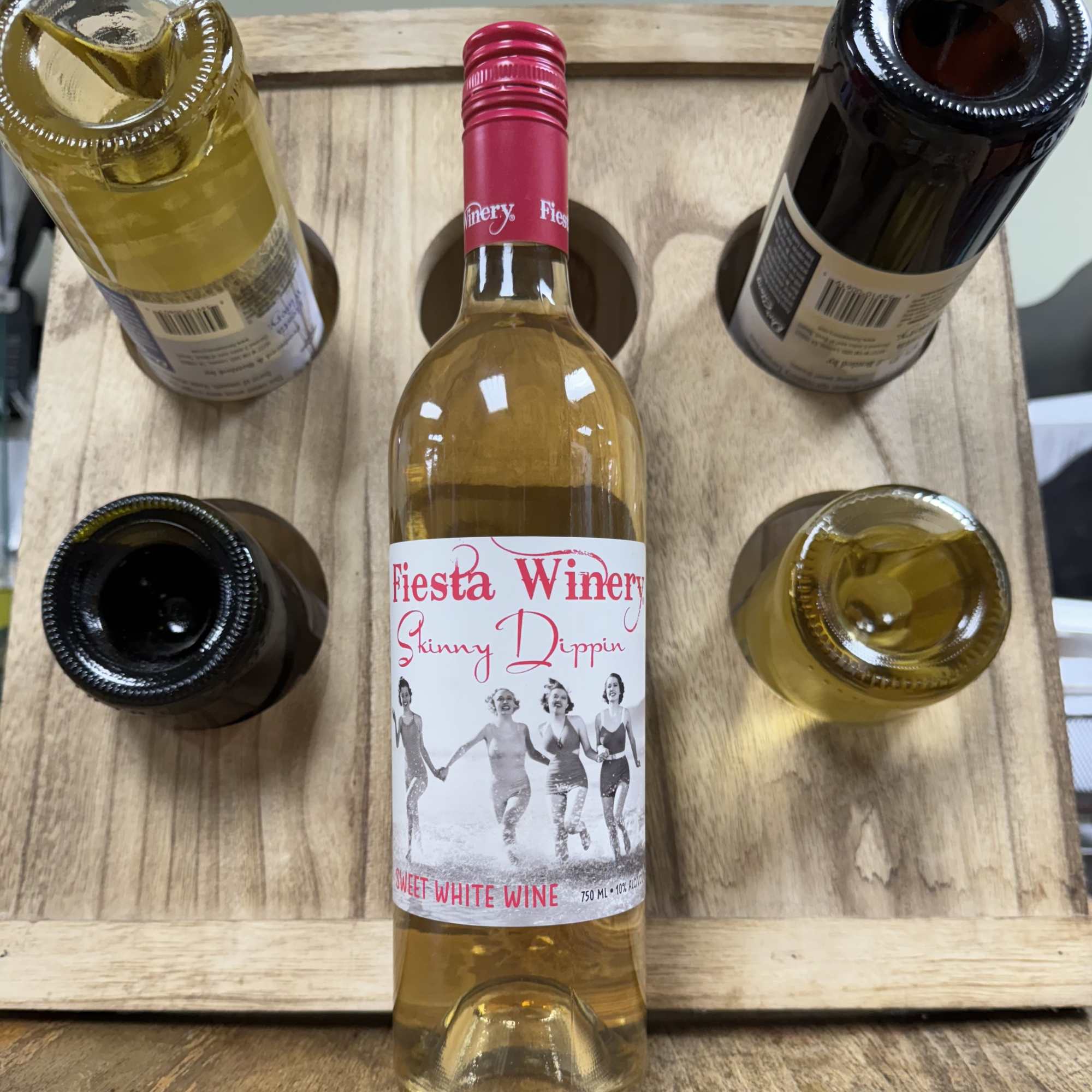 Five wine bottles arranged in a wooden carrier, with one bottle centered in front.