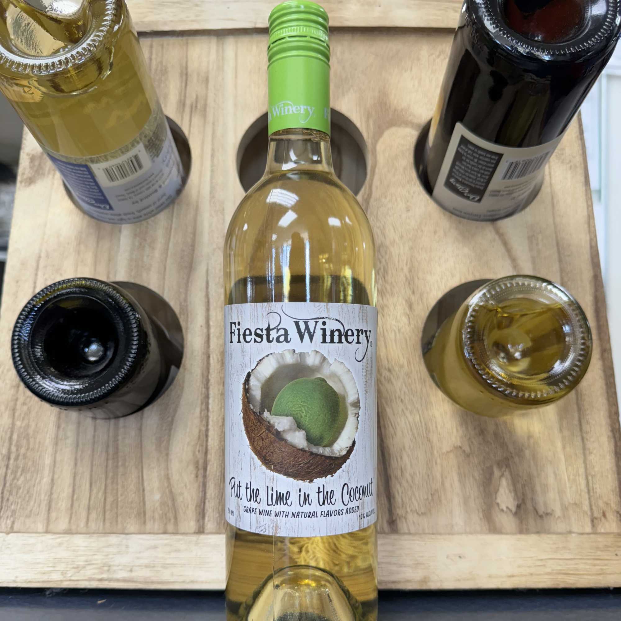 Five wine bottles arranged in a wooden carrier, one labeled Fiesta Winery., photo 8 of 8