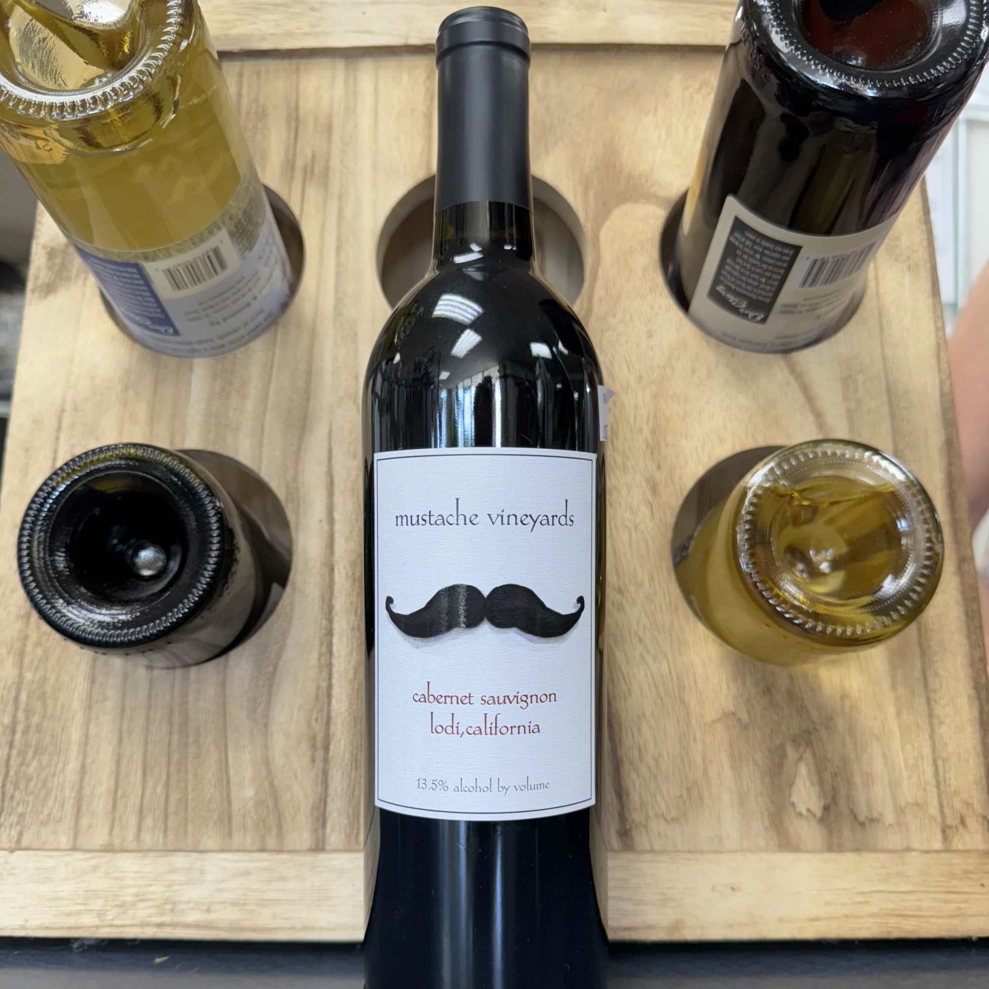 Bottle of red wine in a wooden holder with four other bottles
