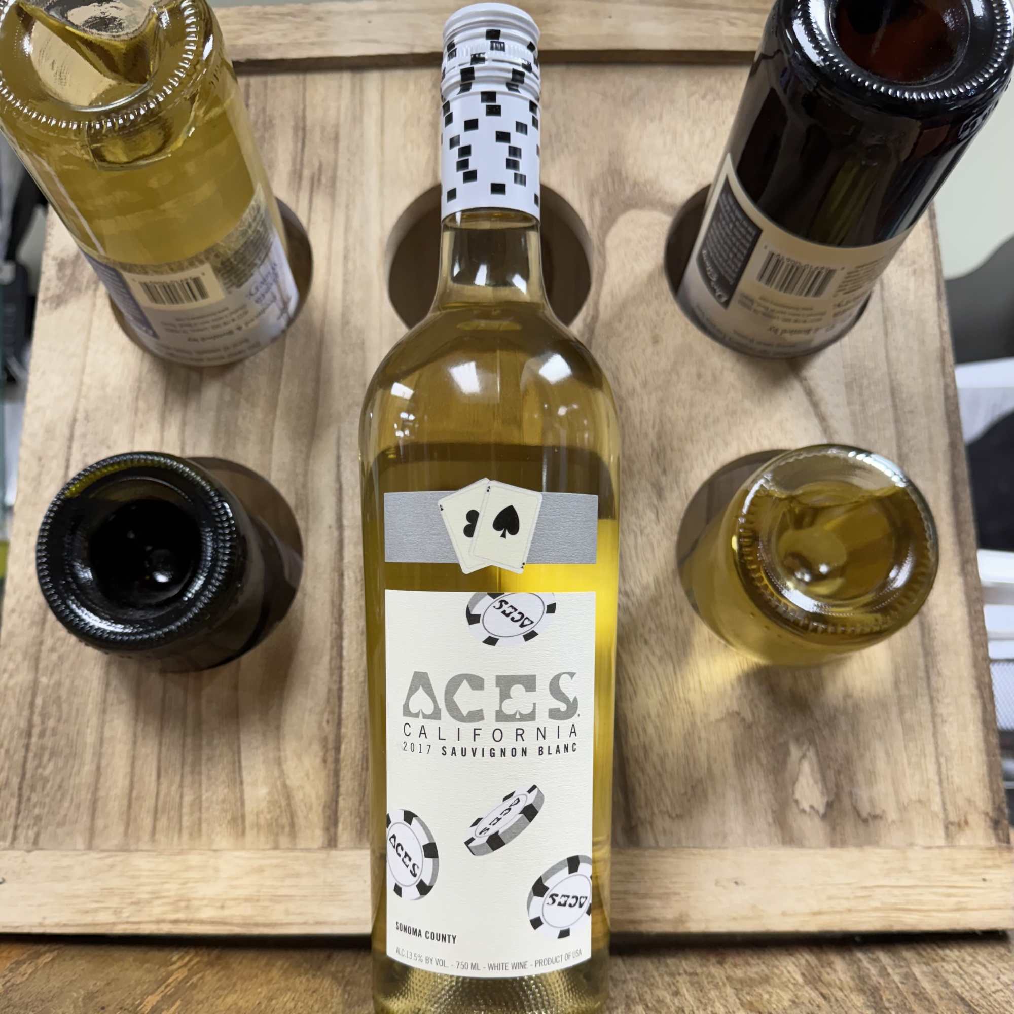 Five wine bottles arranged in a wooden carrier, with one bottle centered in front.