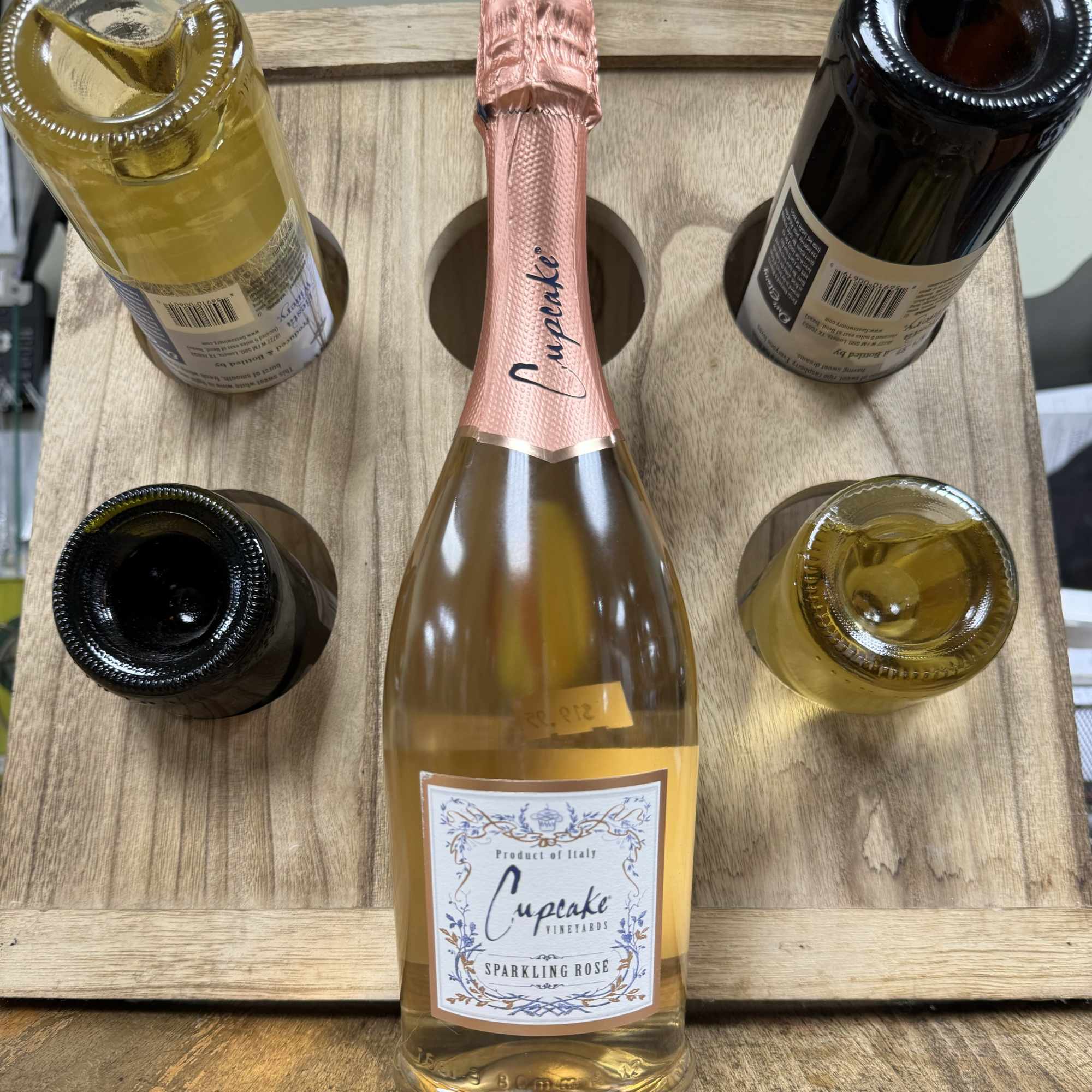 Five bottles of sparkling wine arranged in a wooden carrier
