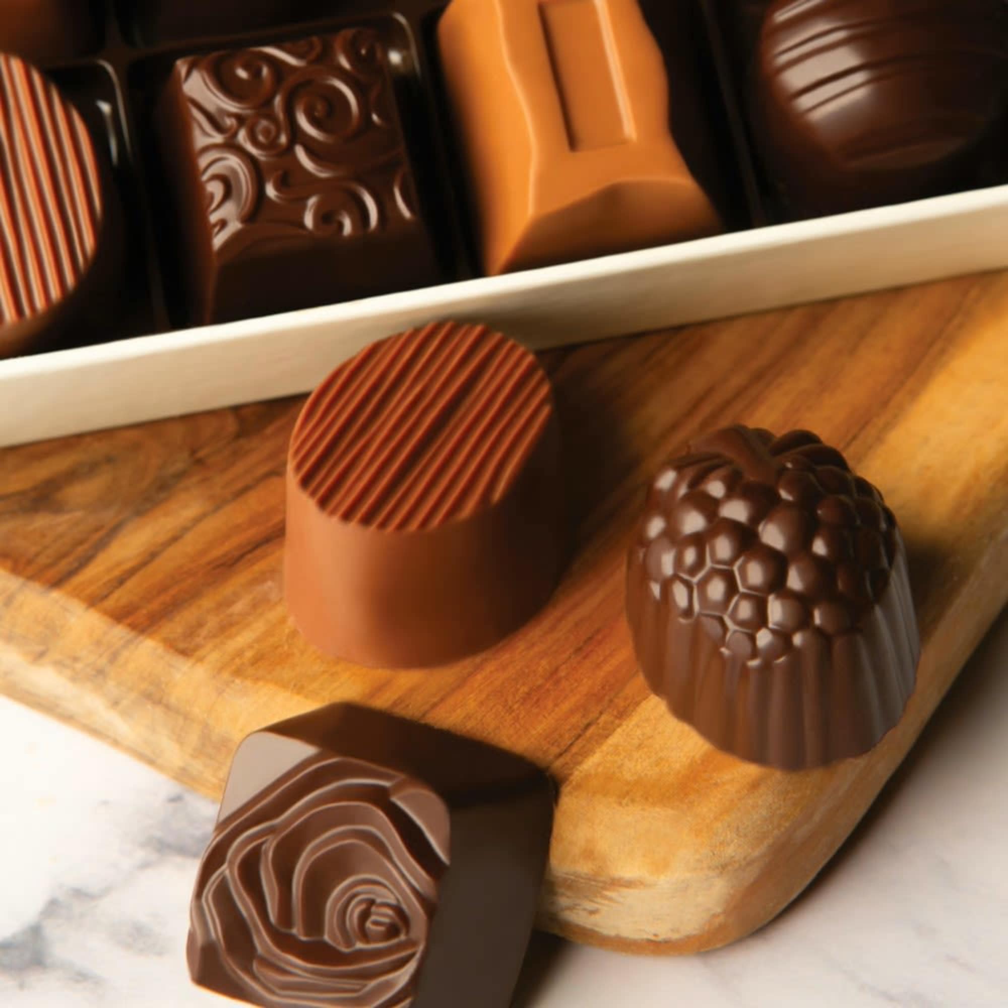 Assorted chocolate truffles in a box on a wooden board