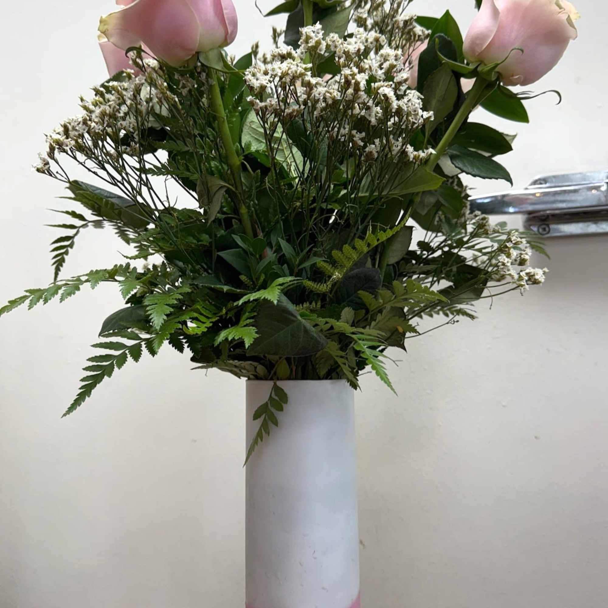 Pink roses arranged in a tall white and pink vase