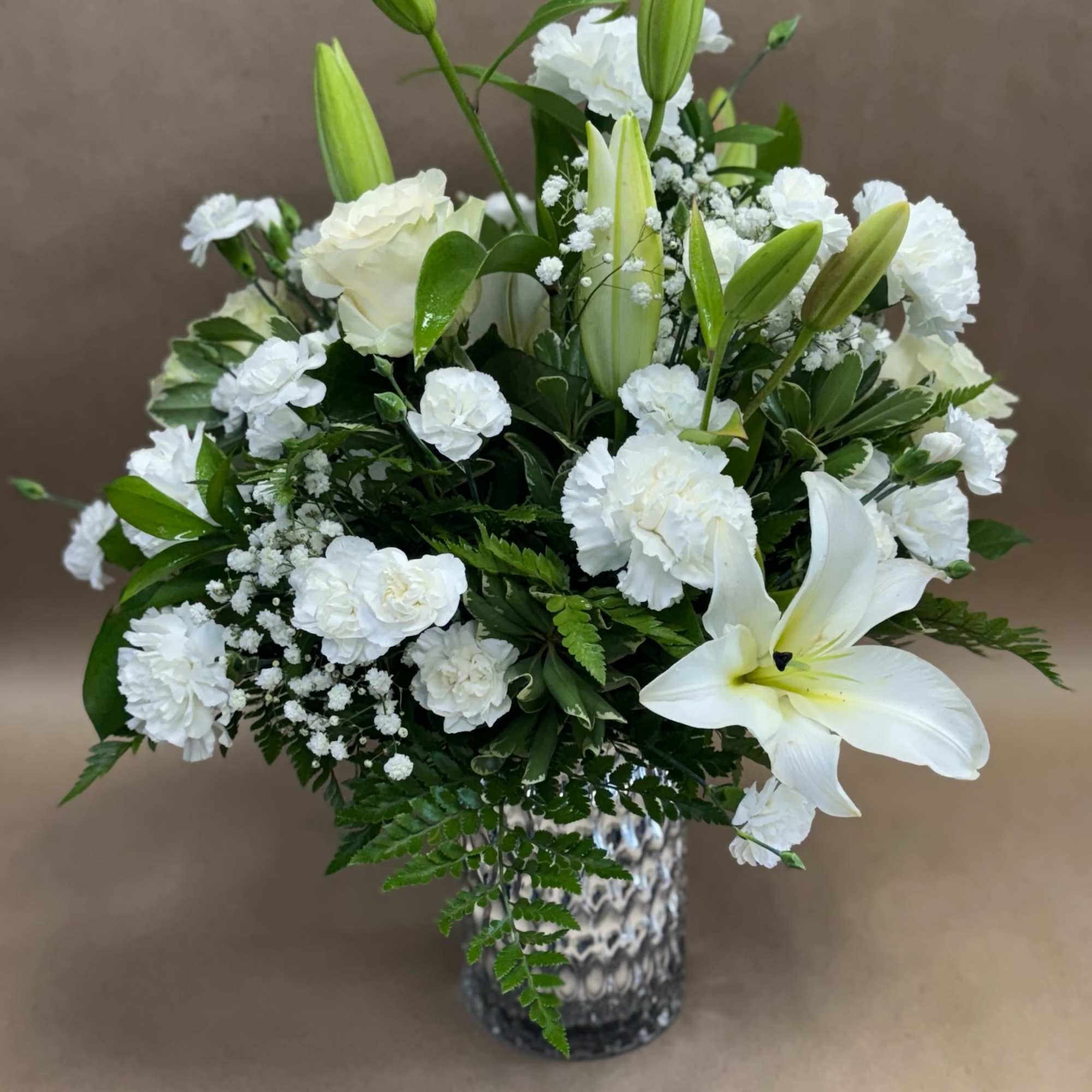 White lilies and carnations arranged in a vase