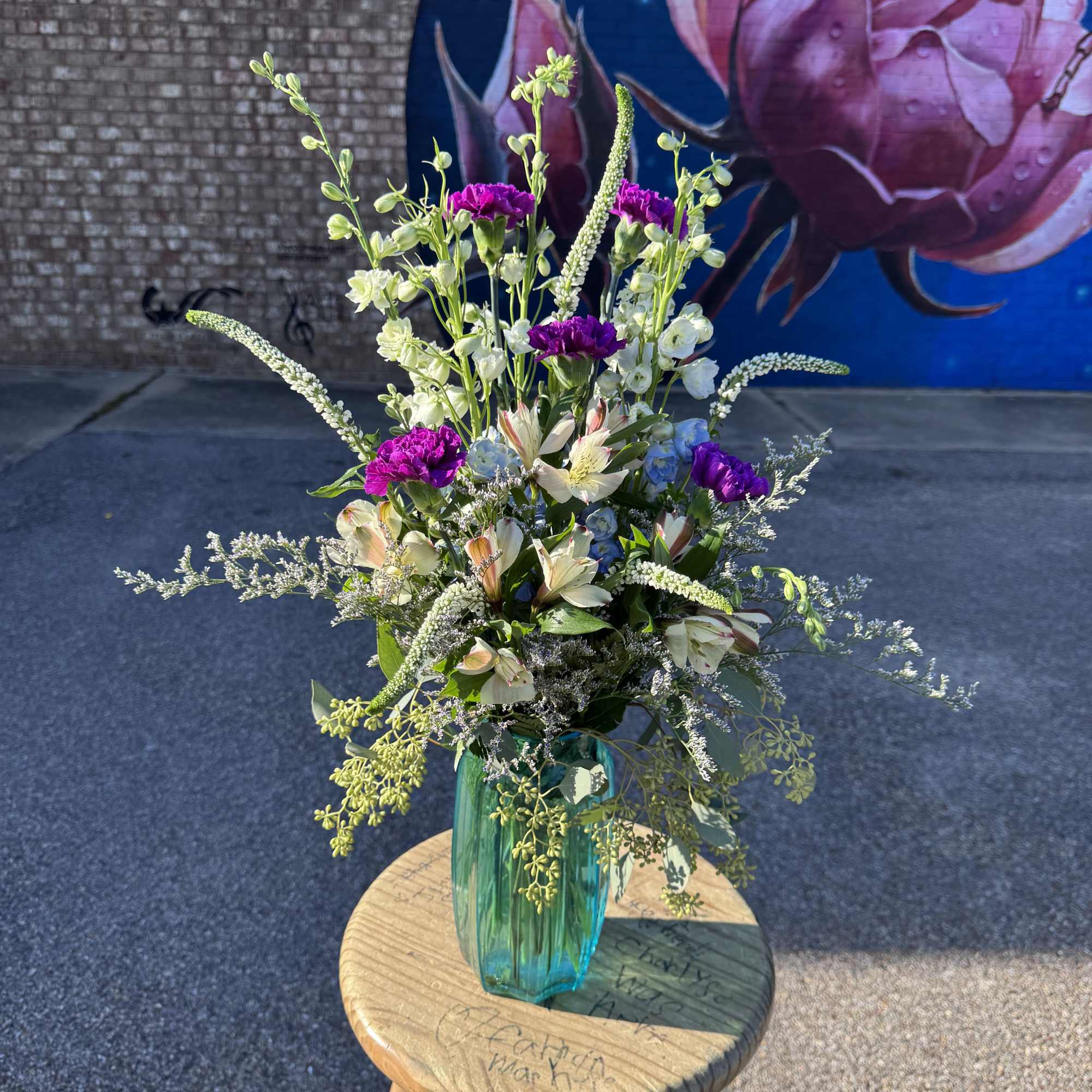 Tall mixed bouquet in a teal glass vase with pink and white blooms