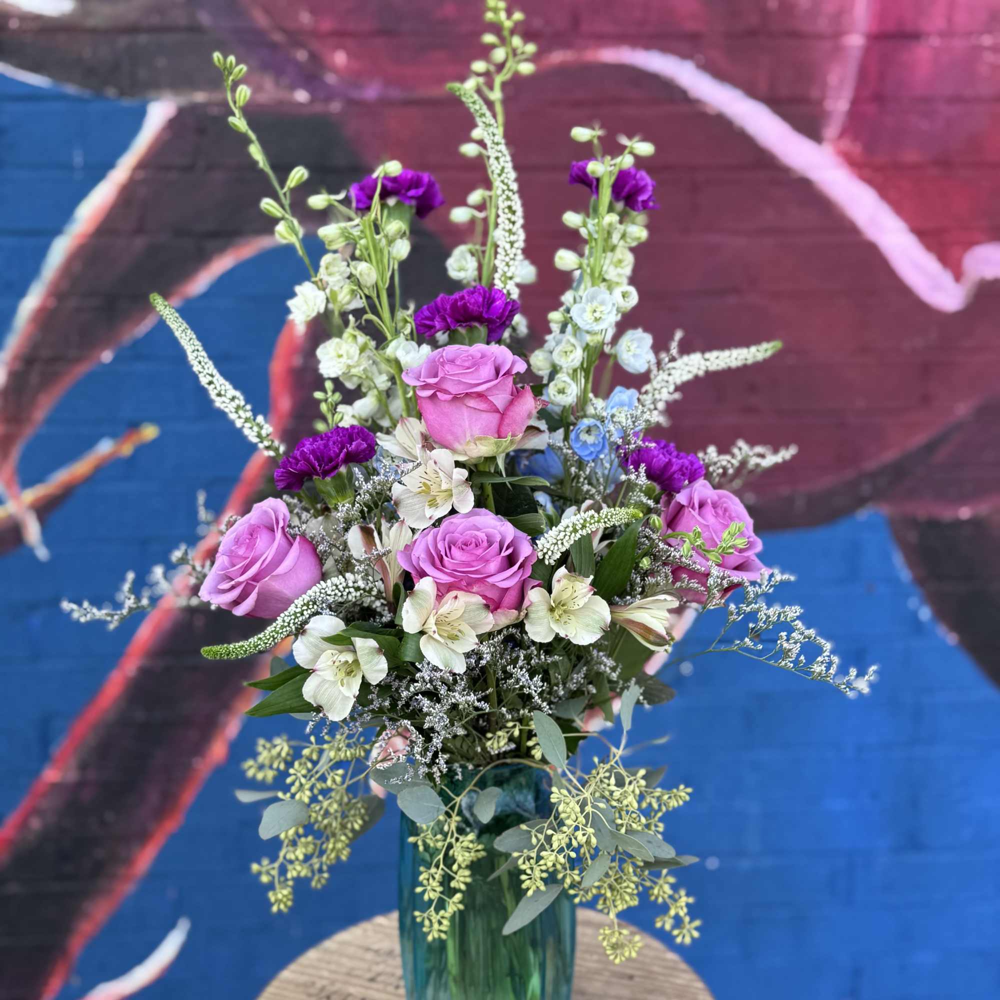 Pink roses and white flowers in a blue glass vase