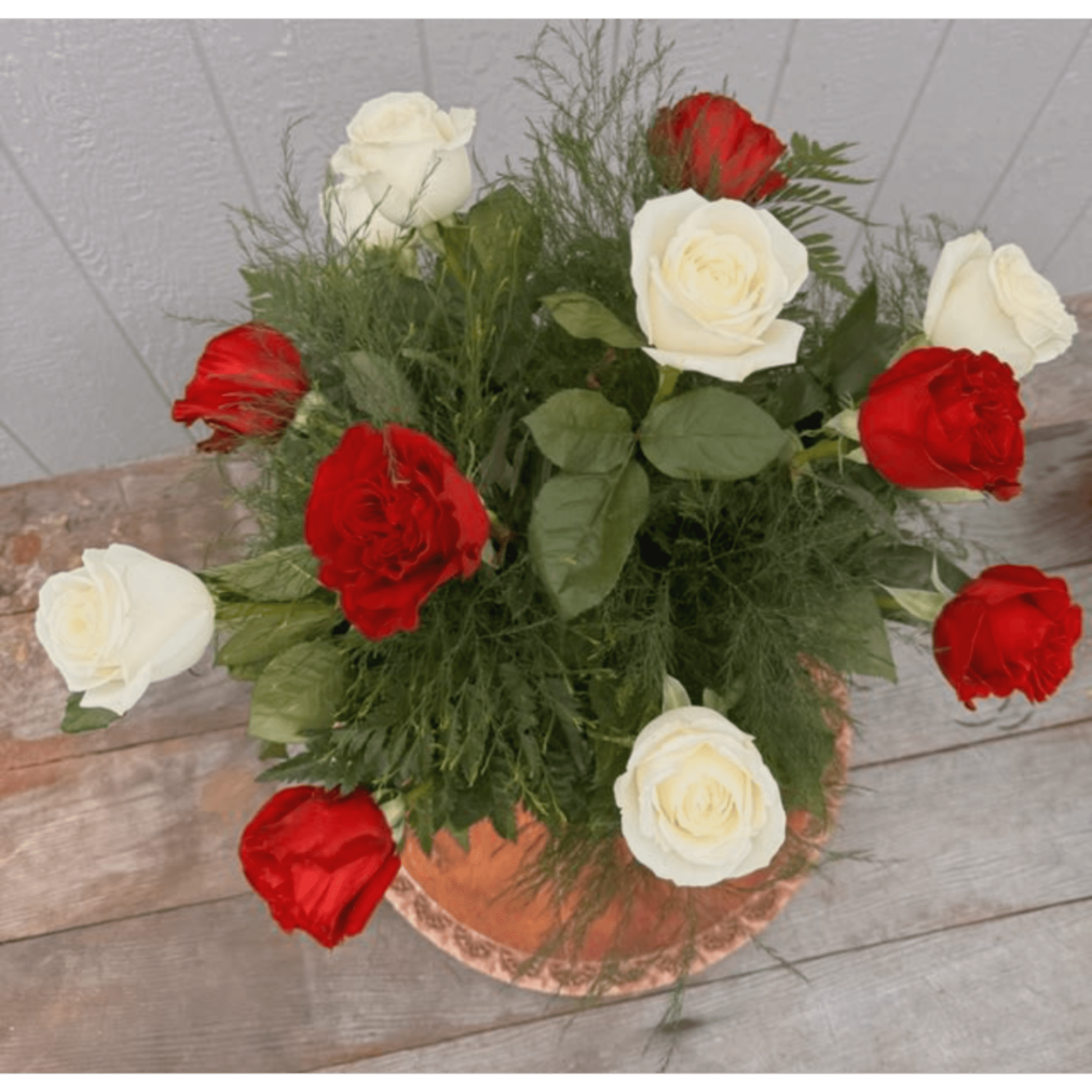 Red and white roses arranged in a copper vase