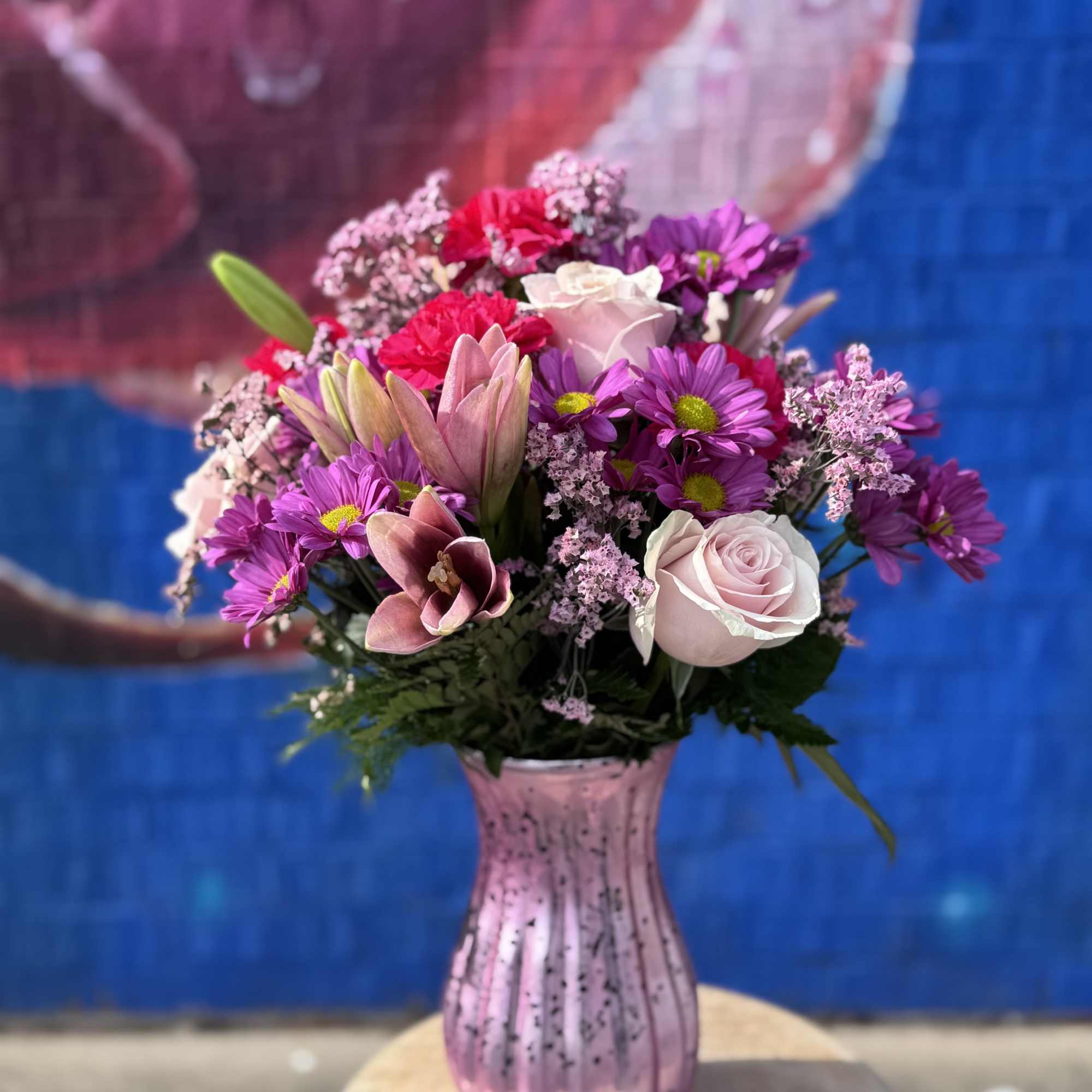 Pink and purple mixed bouquet in a pink glass vase