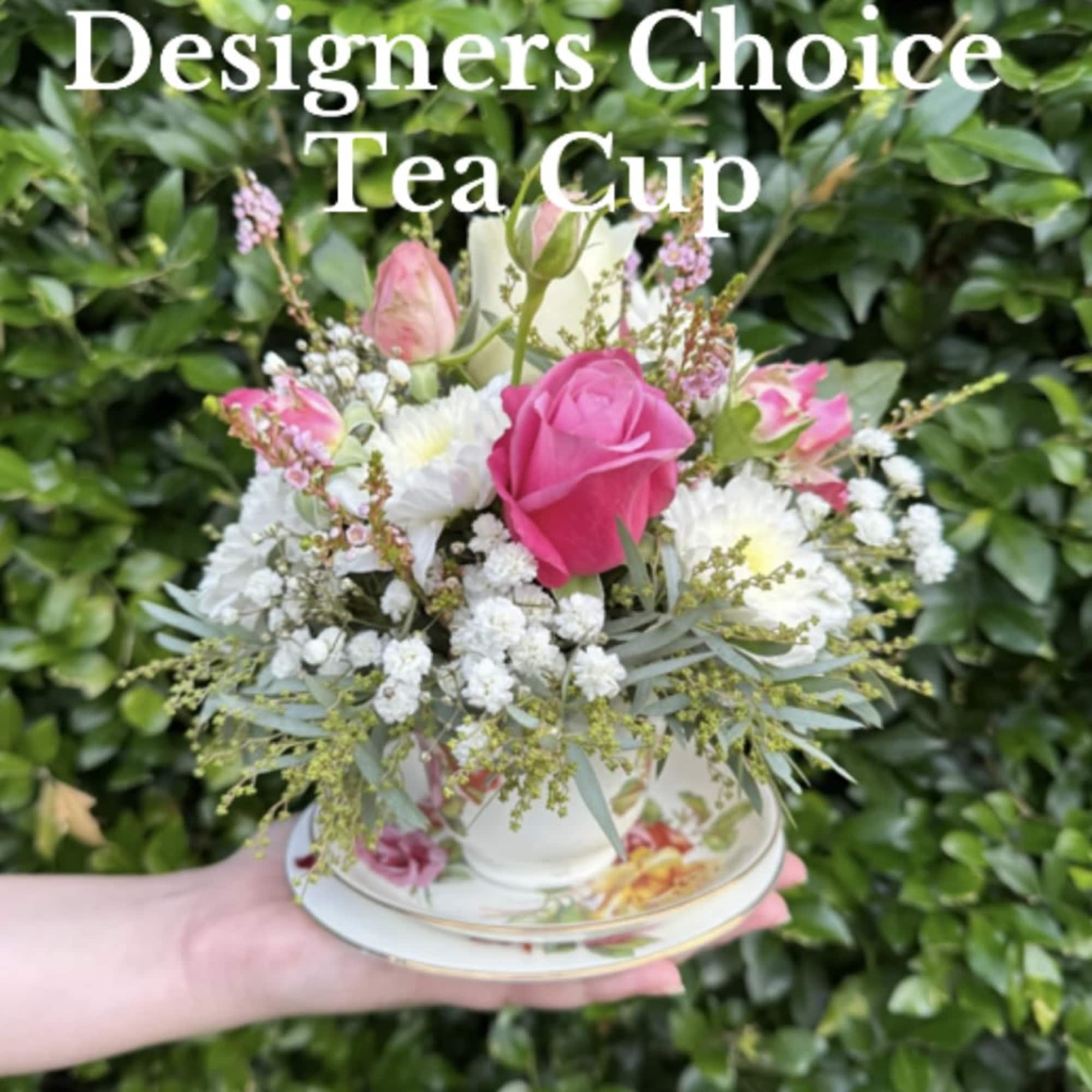 Pink and white flowers arranged in a teacup on a saucer