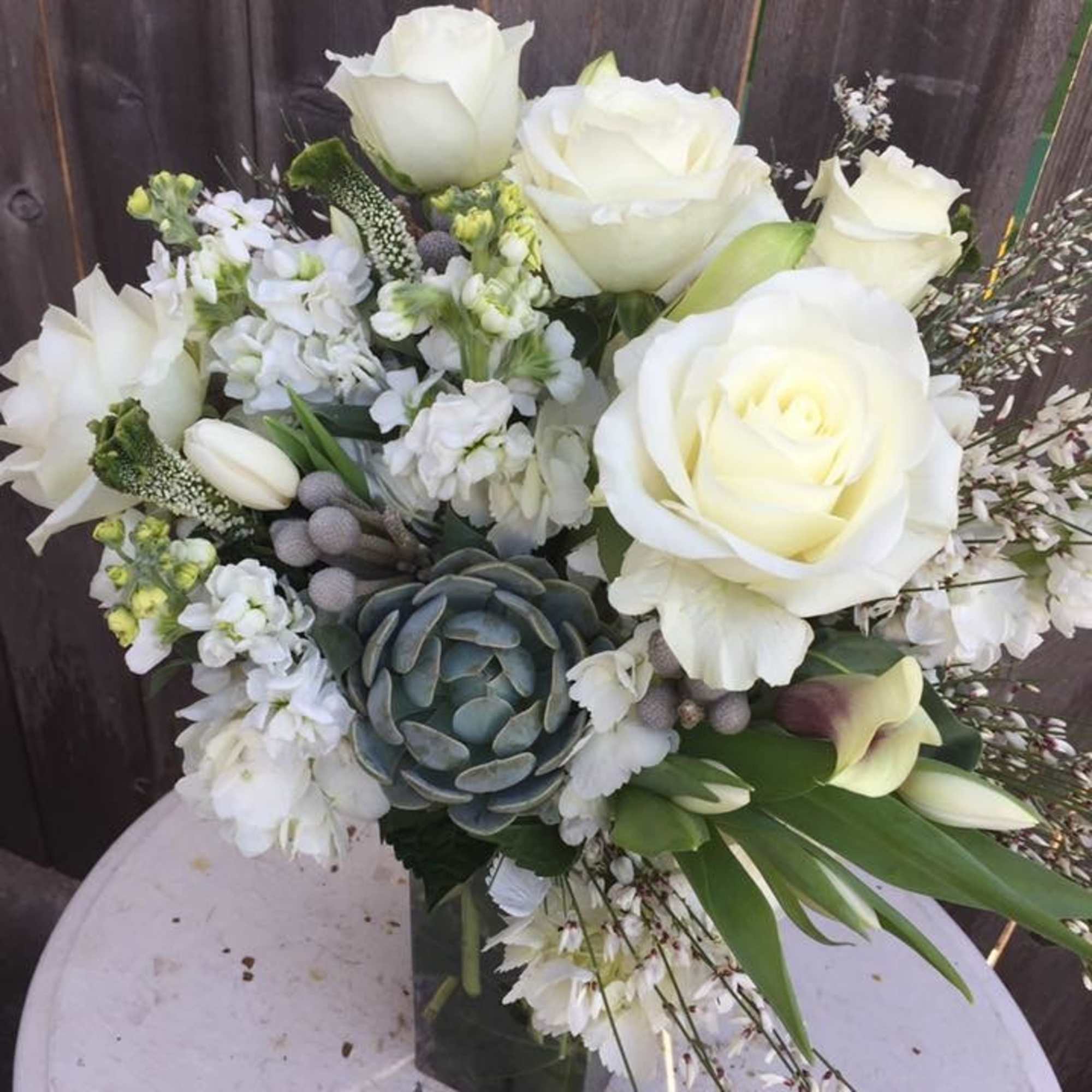 White roses and mixed white flowers arranged in a square vase