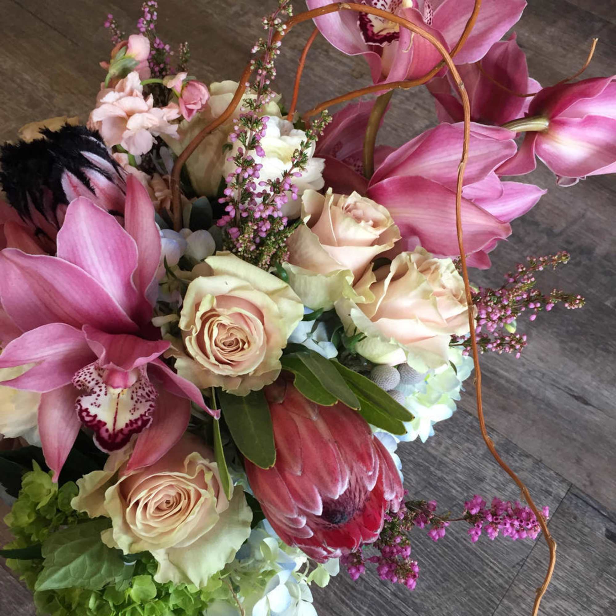Bouquet of pink orchids, cream roses, and a pink protea