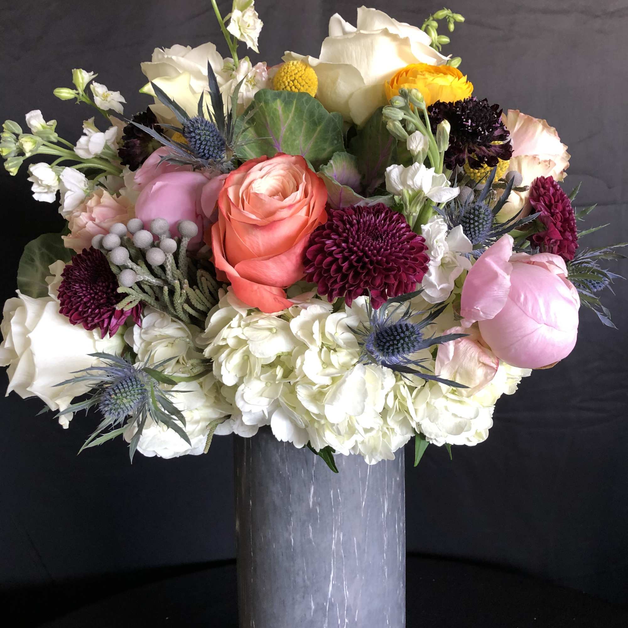 Mixed bouquet in a tall gray vase with pink, white, yellow, and purple blooms