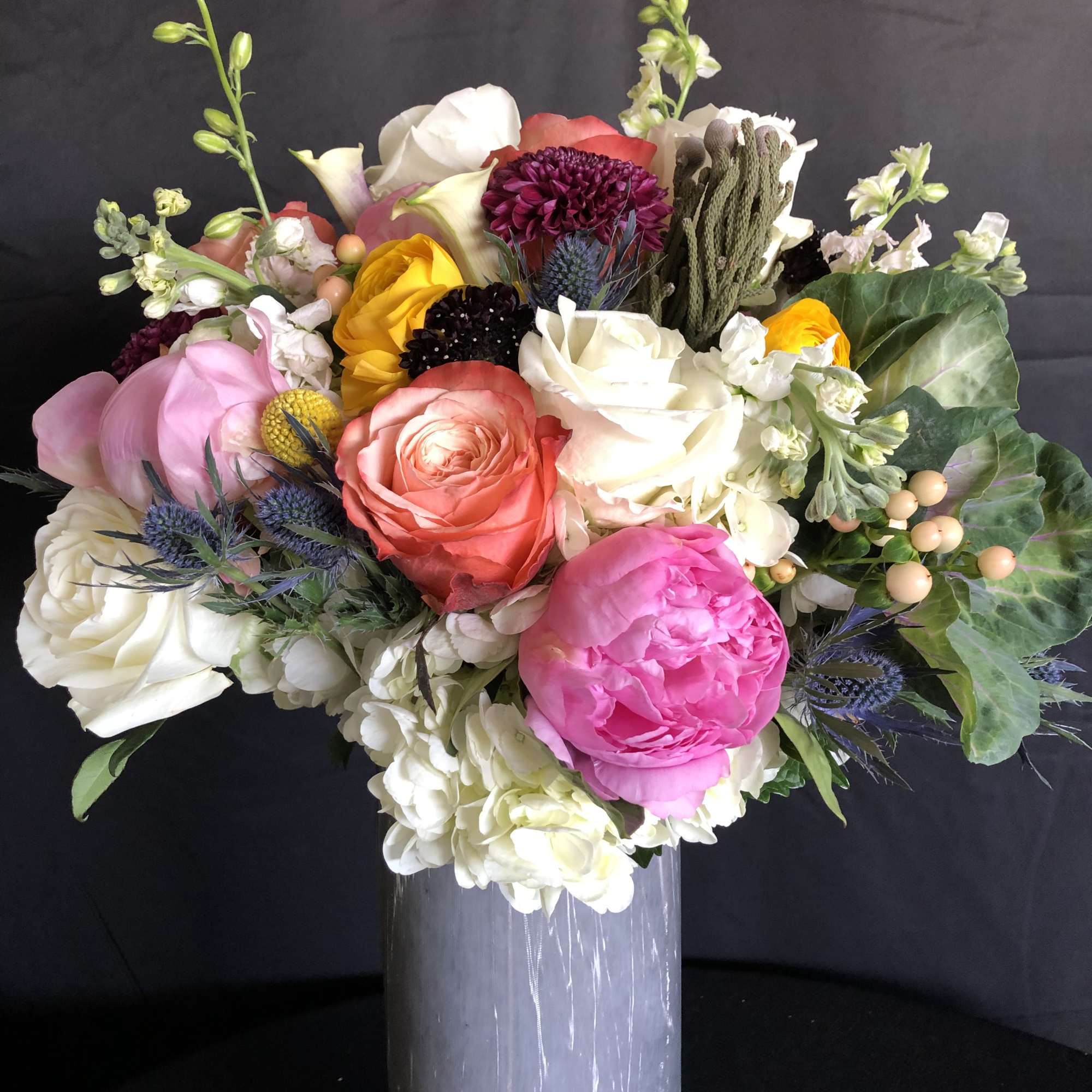 Mixed bouquet of roses, peonies, and hydrangeas in a tall vase
