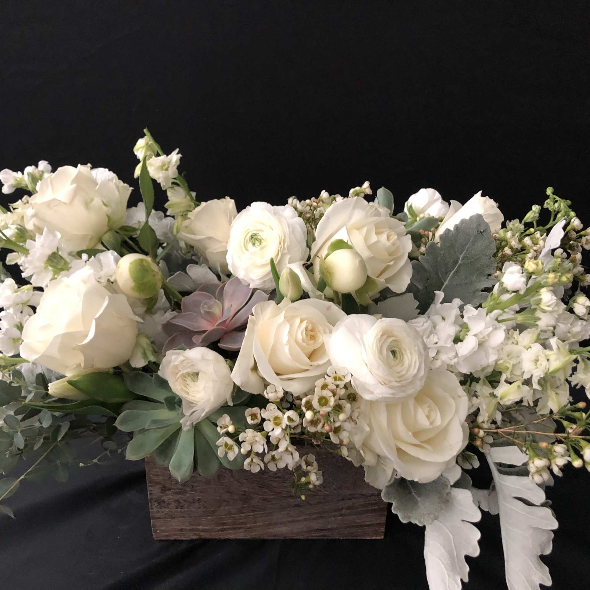 White roses and ranunculus arranged in a wooden box