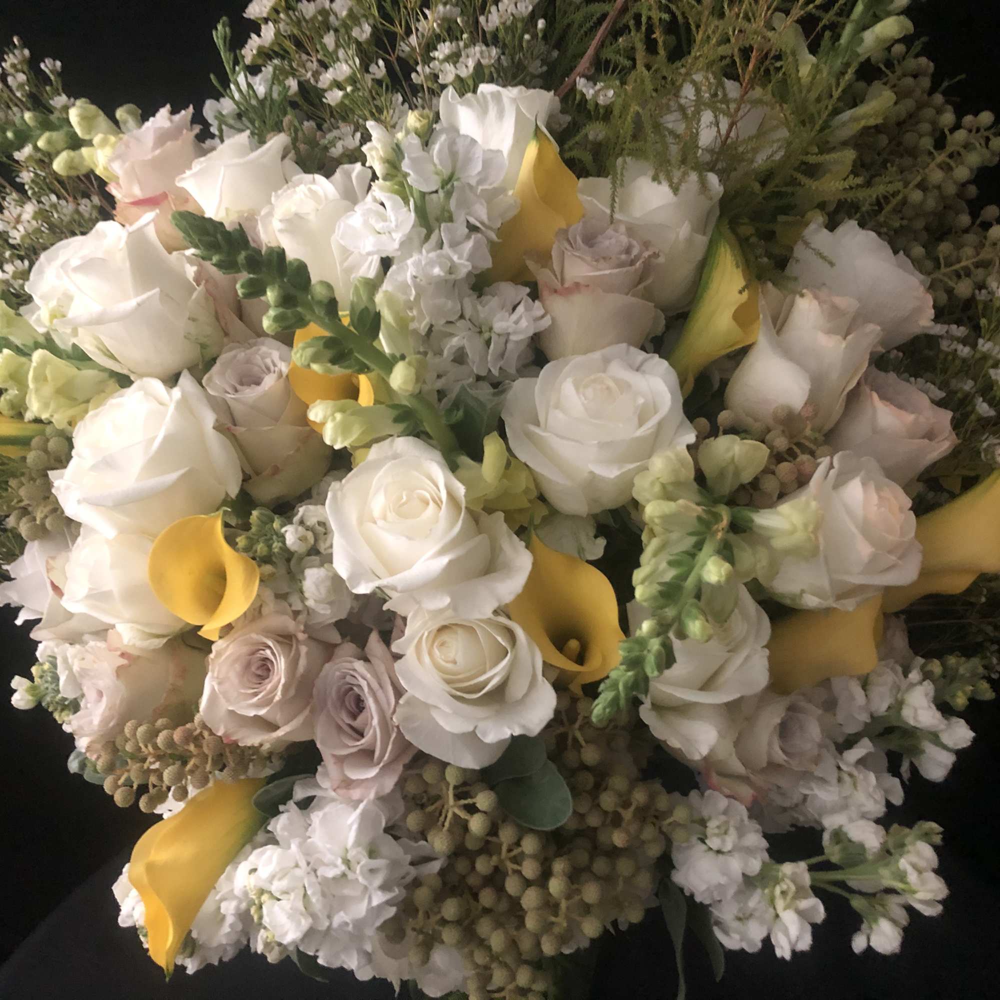 Bouquet of white roses, yellow calla lilies, and pale filler flowers