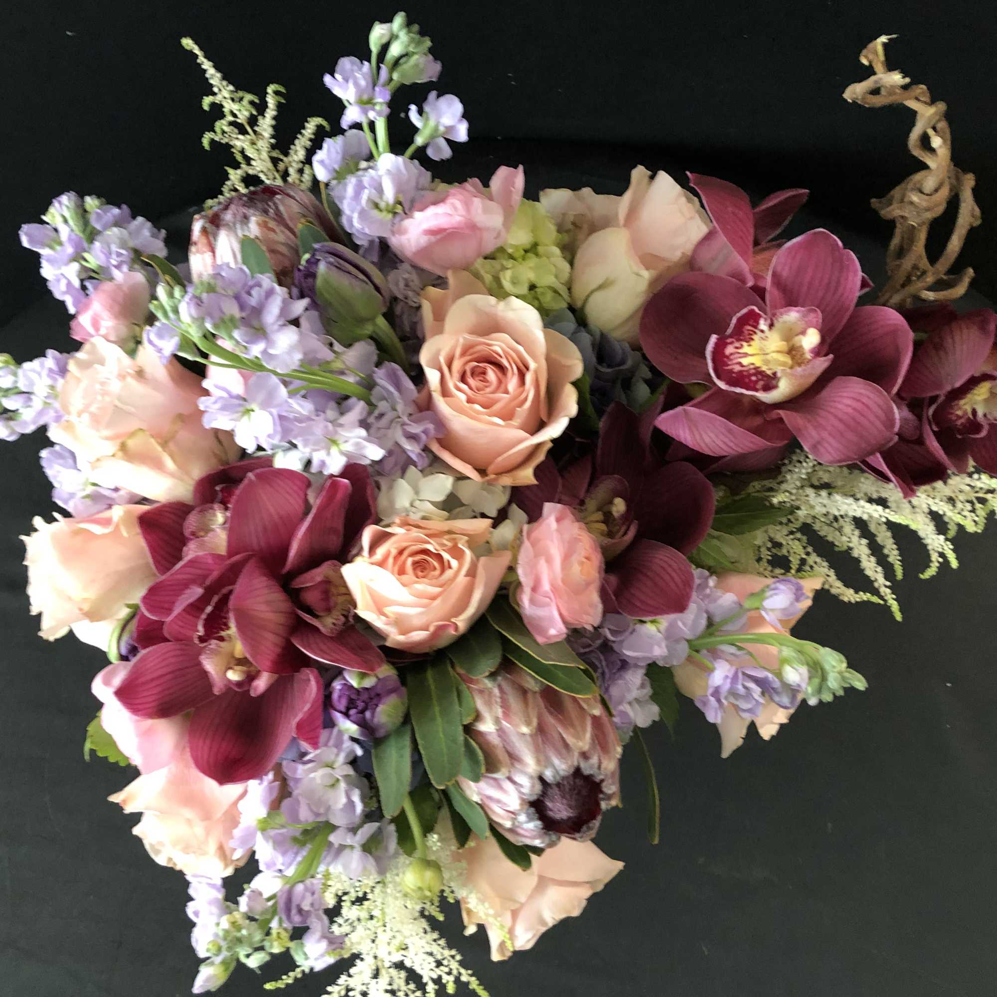 Bouquet of peach roses, lavender flowers, and deep magenta orchids