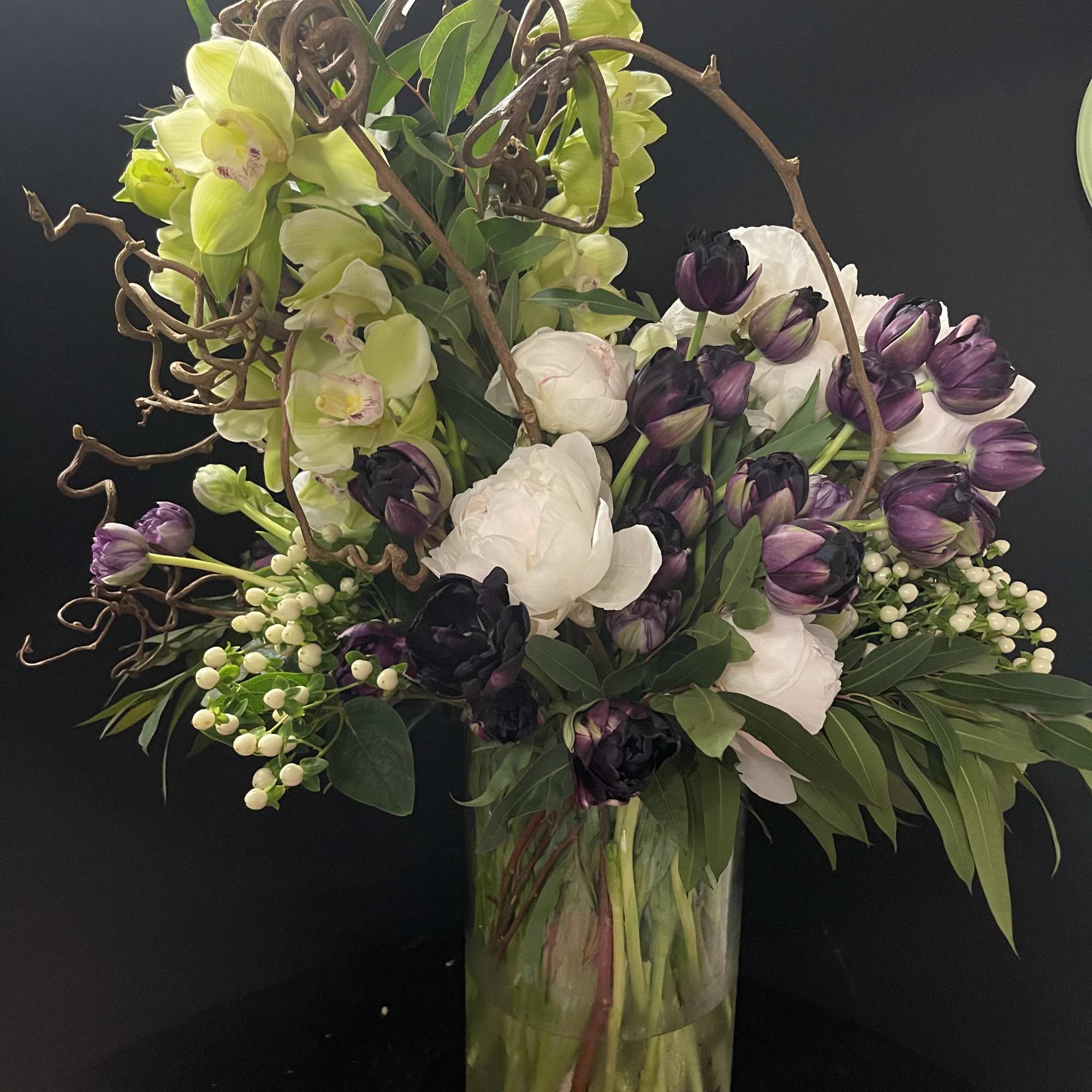 Tall bouquet of purple and white tulips with orchids in a glass vase