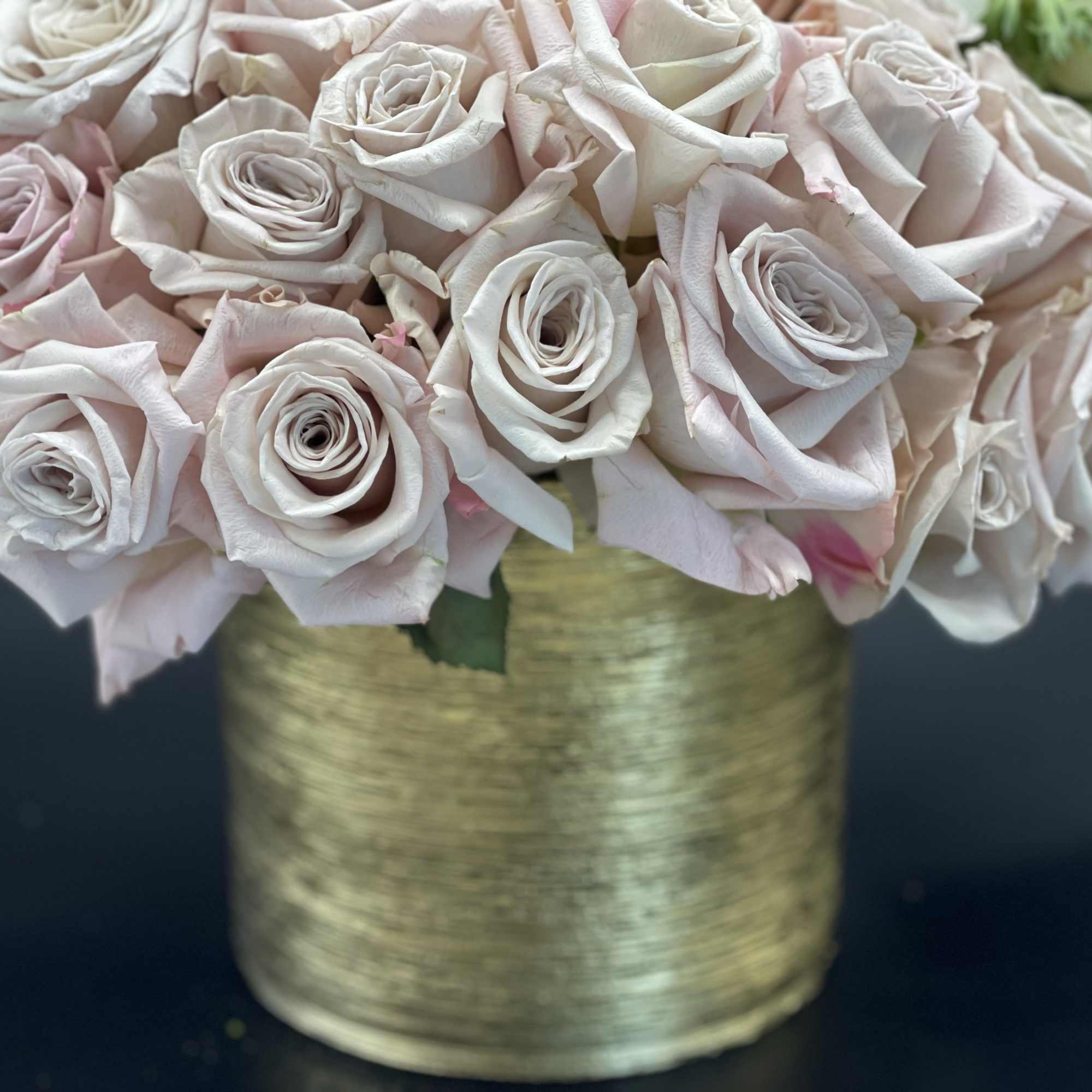Pale pink and white roses arranged in a gold vase