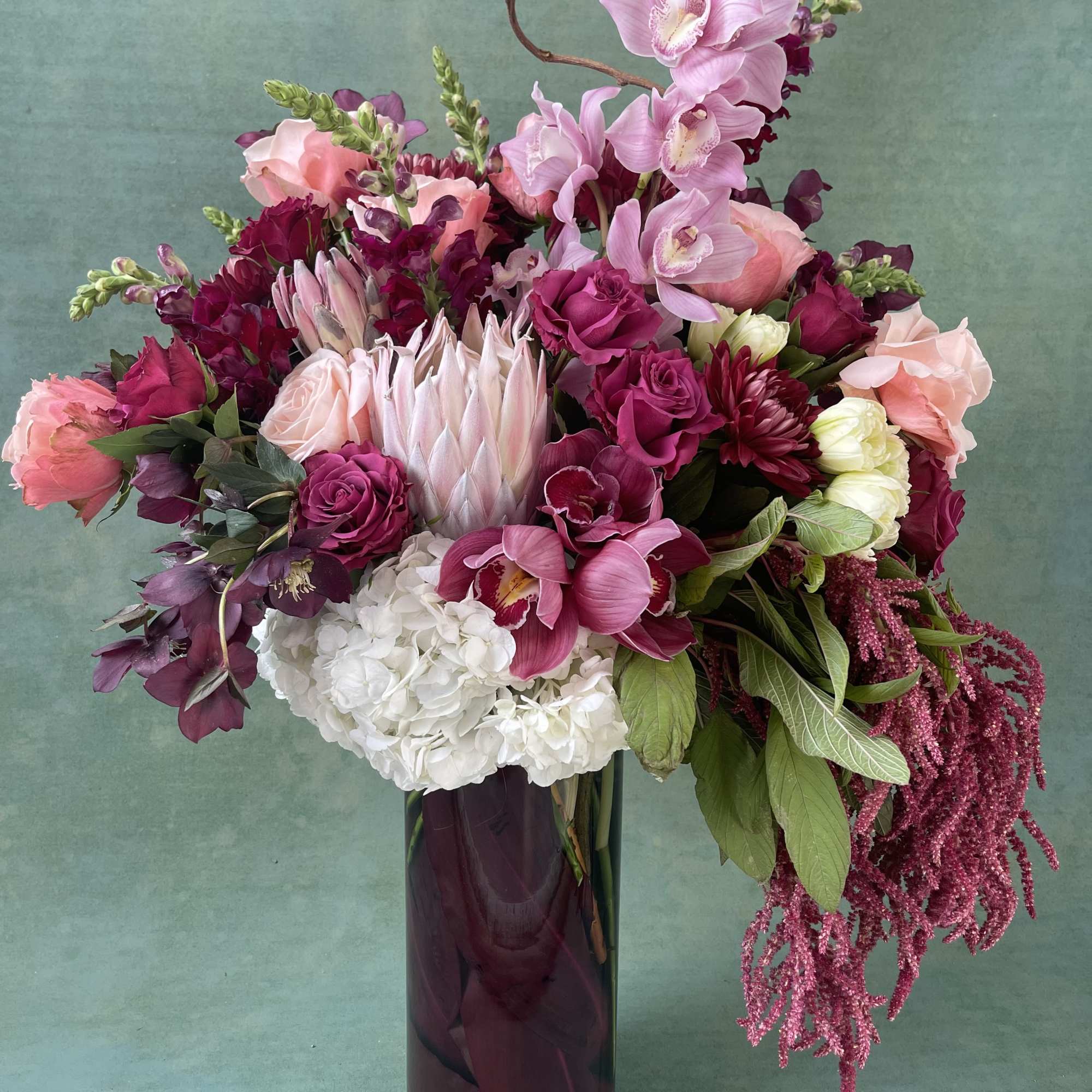Pink and burgundy floral arrangement in a tall dark vase