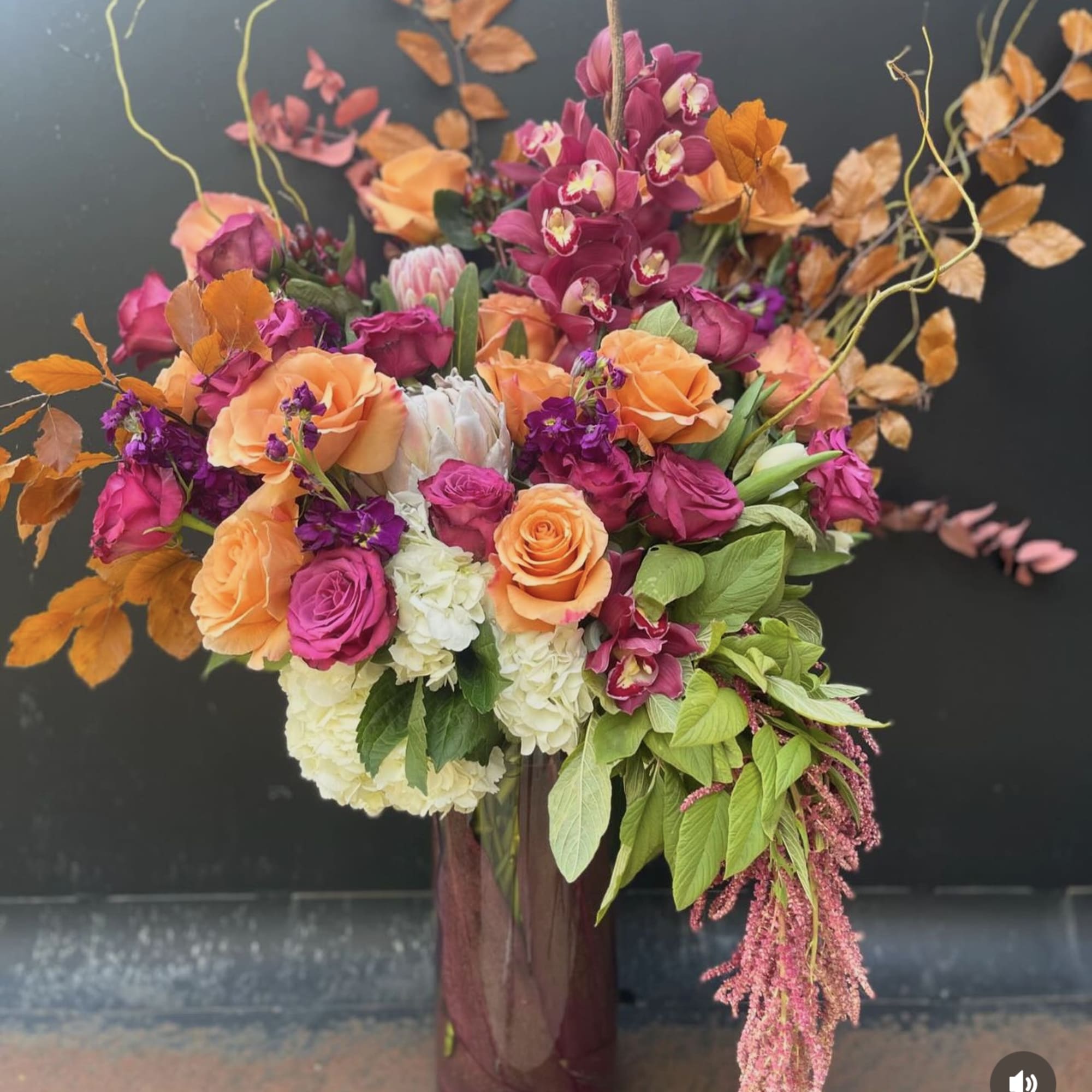 Large floral arrangement with orange, pink, and white blooms in a tall vase