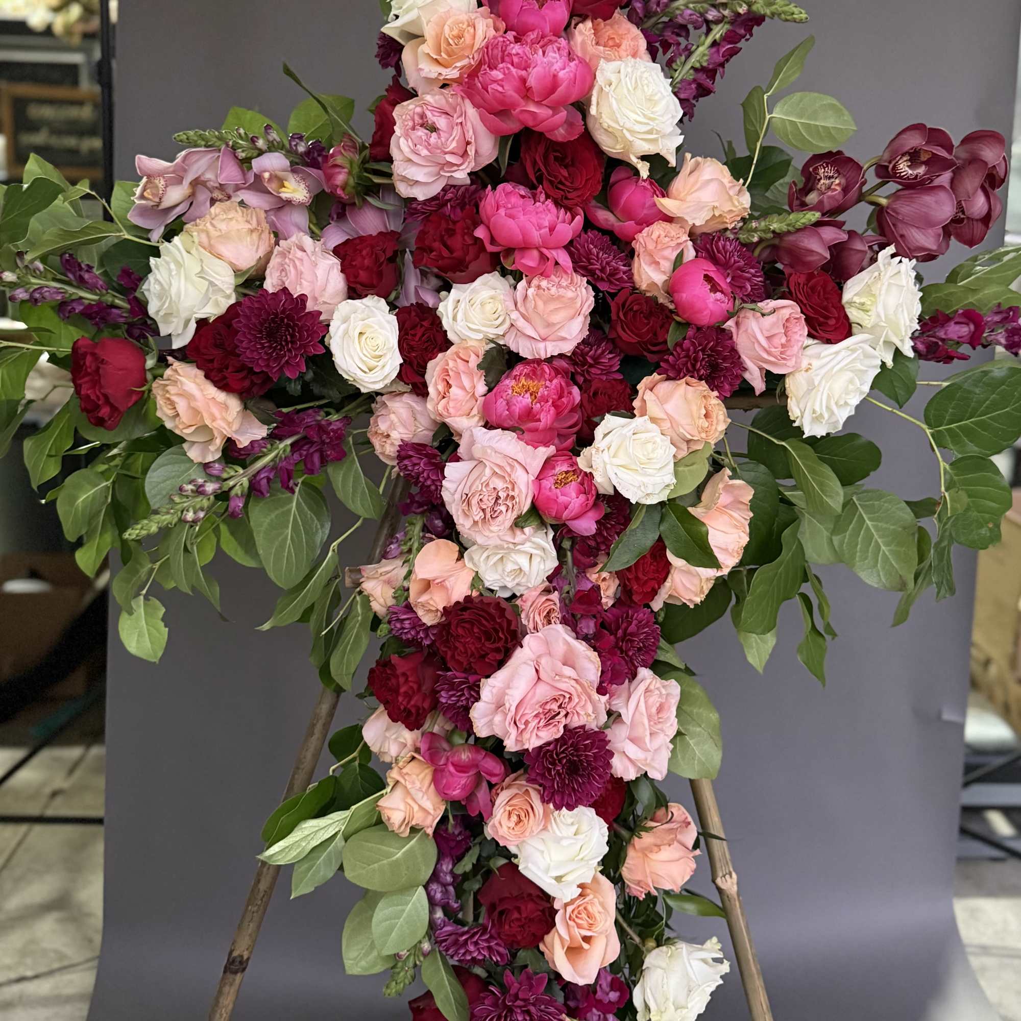Large floral cross with pink, white, and burgundy flowers