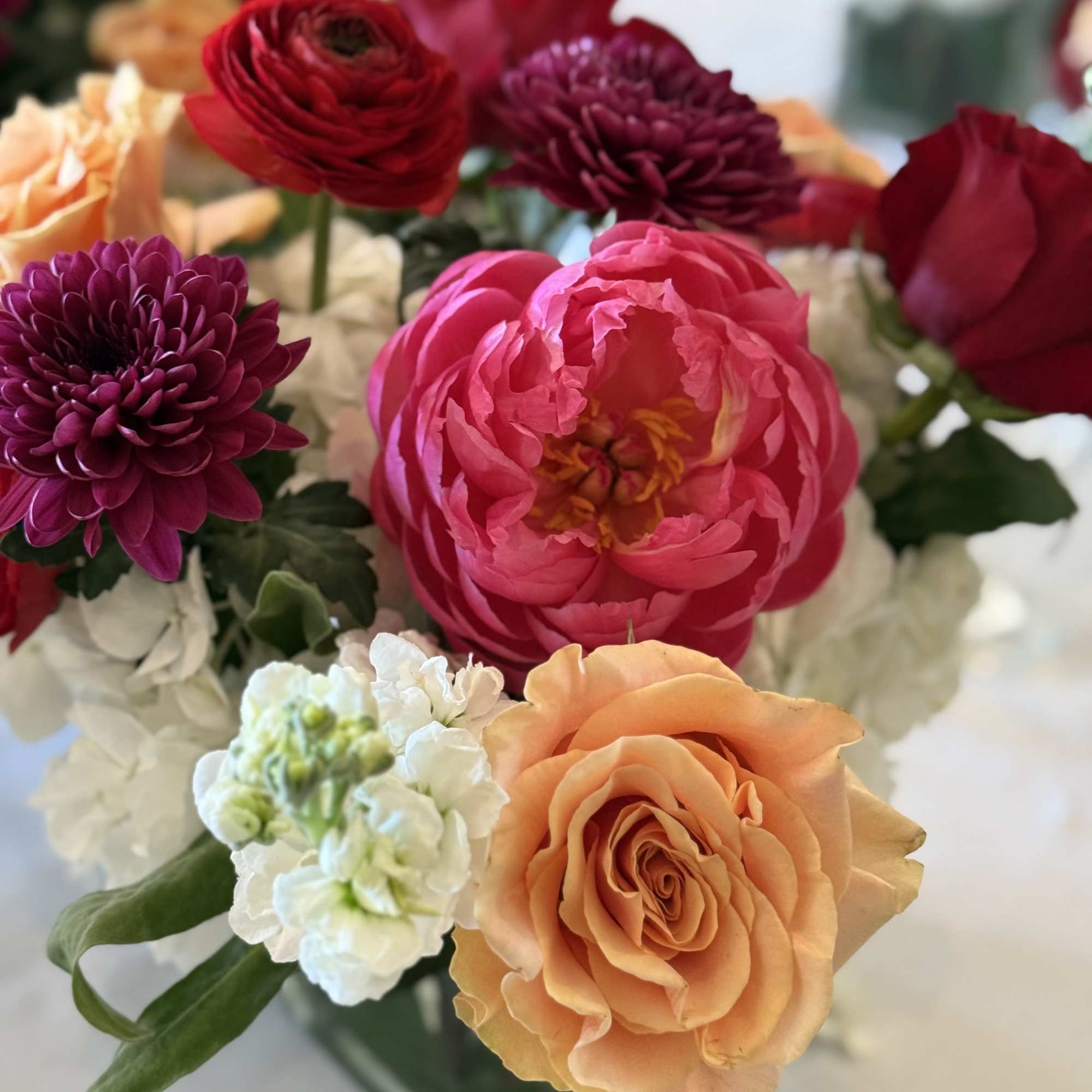 Mixed bouquet of roses, ranunculus, and chrysanthemums in a vase